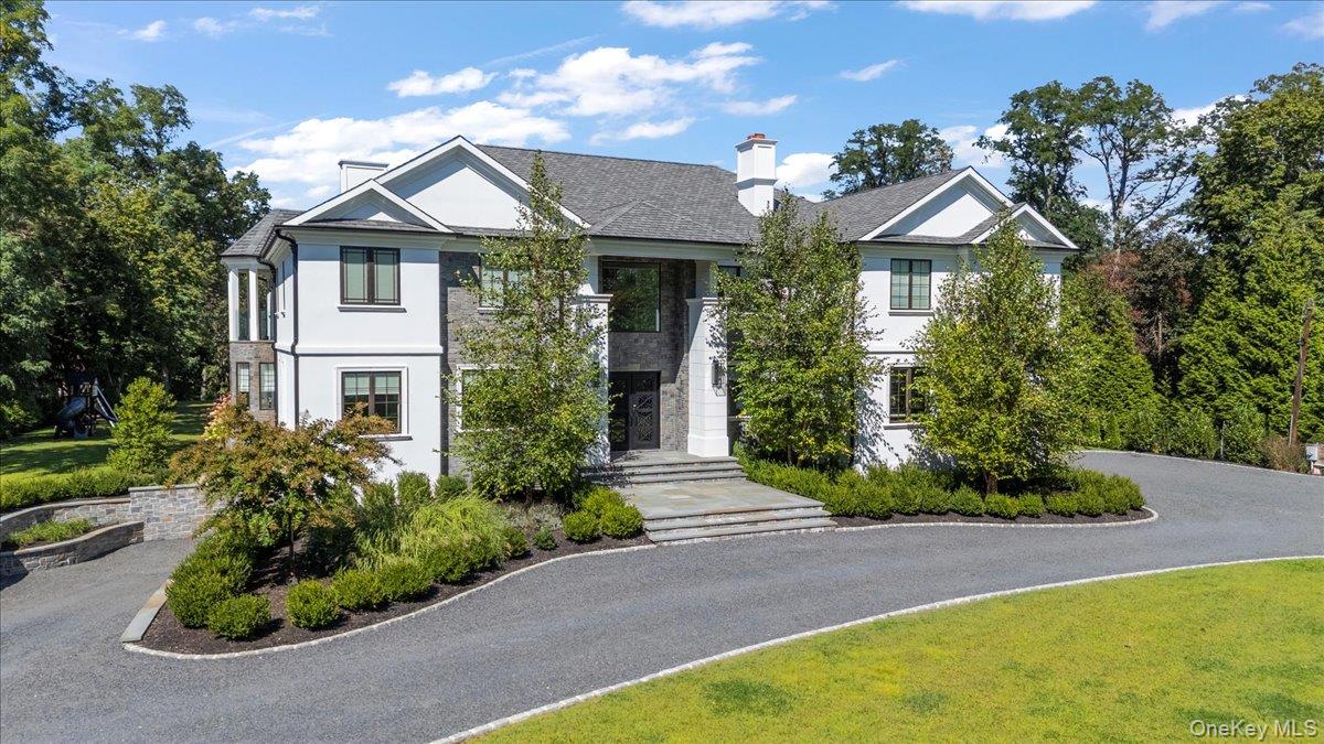 Welcome to 5 Gerry Lane, an extraordinary new construction in the prestigious Village of Lloyd Harbor. Set on two landscaped acres, this almost 8,500 sq. ft. custom residence was designed with today’s modern lifestyle in mind, offering five en-suite bedrooms, 6.5 baths, and striking architectural details throughout. At the heart of the home is the chef’s kitchen, featuring Thermador appliances, Calcutta Oro marble countertops, island and backsplash.  The large center island has seating for four, a sunlit breakfast nook for six, and space for a dining table that can host twelve—ideal for both intimate gatherings and large-scale entertaining. The open floor plan flows effortlessly into the great room, while wide-plank wire-brushed white oak floors add warmth and sophistication throughout. A first-floor en-suite bedroom with direct yard access provides flexibility for guests or extended family. Upstairs, the primary suite is a true retreat, offering a sunlit walk-in closet and a spa-inspired bath with radiant-heated marble floors, soaking tub, and custom shower. Three additional oversized en-suite bedrooms complete the second level, with rear-facing suites opening to a glass-lined balcony overlooking the grounds. The finished lower level enhances the lifestyle with a recreation room, professional gym with full-height windows, and a driveway-accessed garage bay designed for the car enthusiast—perfect for showcasing rare automobiles. Outdoors, the home is framed by bluestone patios and walkways, Belgian block curbing, a crushed bluestone driveway, in-ground sprinklers, and lush landscaping. A circular driveway with automatic gates provides additional privacy and presence. Residents enjoy membership in the exclusive Hawk Beach Association, with private beach access and dock use for moored boats. Ideally located near Caumsett State Park, village beaches, and the shops and dining of Huntington and Cold Spring Harbor, with the Cold Spring Harbor train station offering a convenient 55-minute commute to Manhattan. 5 Gerry Lane delivers the perfect blend of luxury, lifestyle, and location in one of Long Island’s most coveted communities.