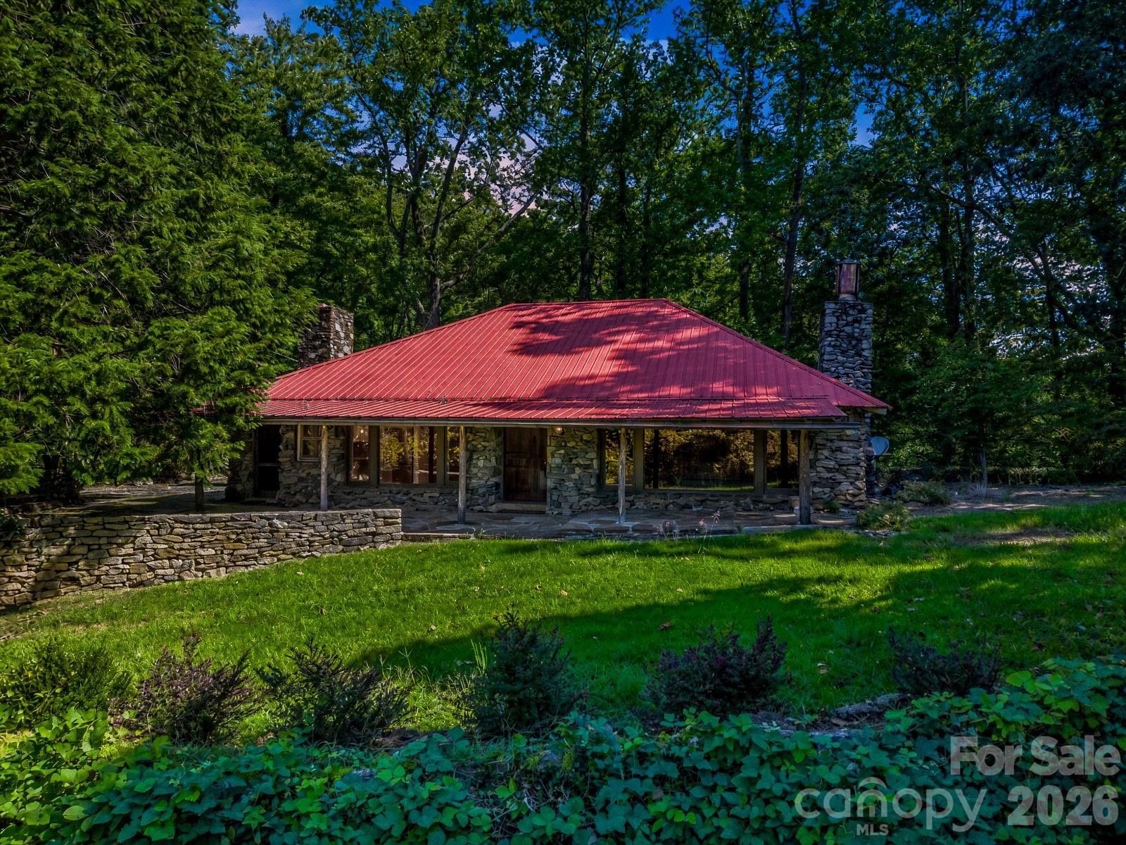 Beautifully updated and full of timeless character, this 1937 stone home blends historic charm with modern comfort on 11.24 private acres in Tryon. Offering approximately 3,000 square feet, the home features 3 bedrooms, 2.5 baths, main-level living, and a finished basement for added flexibility.Original old-world details have been thoughtfully preserved, including pickled chestnut wood paneling, pine floors, and a wood-burning fireplace in the living room. Tasteful updates complement the home’s classic appeal, creating a warm and inviting atmosphere throughout. The main level provides comfortable everyday living, while the finished basement expands the usable space with durable LVP flooring and room for recreation, guests, hobbies, or a home office.The kitchen and baths have been updated to support modern living while maintaining the home’s distinctive personality. Tile bathrooms add style and durability, and each space balances charm and function.Outdoor living is a true highlight of this property. Numerous stone patios provide multiple places to gather, entertain, or relax in the peaceful natural surroundings. A covered front porch welcomes you home, while the outdoor fireplace creates the perfect setting for cool mountain evenings. The setting offers exceptional privacy and a sense of retreat, with 11.24 acres to enjoy.A detached 2-car garage adds convenience and storage. Whether you are looking for a full-time residence or a private mountain getaway, this one-of-a-kind stone home offers rare character, updated comfort, and a beautiful setting in the heart of Tryon.