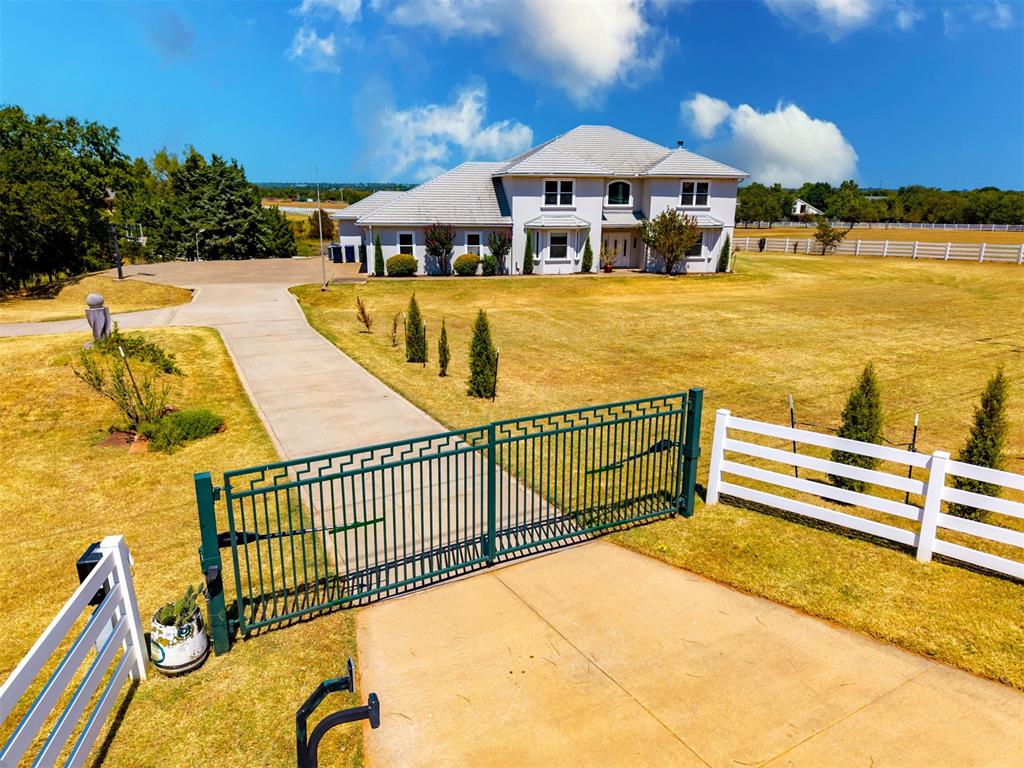 This beautiful European style home sits on an amazing private gated acreage. Enjoy the beautiful views from your patio, pool or hot tub area! Step inside to see the dramatic open concept floor plan with a wall of windows to view the outdoors from living, dining and kitchen areas! The two-story great room includes a built-in wet bar and adjacent television/entertainment area. That along with the elegant statement chandelier in the dining area creates a distinctive space for entertaining. Primary suite includes access to outdoors plus a huge private bath and walk-in closet. Additional second bedroom downstairs has adjacent private bathroom for guests or use as second primary bedroom. A very large and unique utility room includes laundry with washer/dryer, sink & folding area, plus built-ins, pantry and built in wine fridge. A contemporary open-riser staircase with sleek cable railing rises to an upper level gallery overlooking the downstairs great room. Upper level includes two additional bedrooms that share a bathroom with walk-in shower and double vanity. Also enjoy the bonus room as a recreation space, a second living or a 5th bedroom. From this room step outside on the covered deck to enjoy an expansive view of your property. Outdoors includes the attached garage plus a 3 car garage workshop! Home feels like you are at country estate as you sit on the very large terrace deck area and enjoy distinctive views of your own swimming pool, pastures and neighboring pond. Extremely energy efficient home was built with insulating concrete forms and stucco finish. This adds tornado, fire and bug resistance.