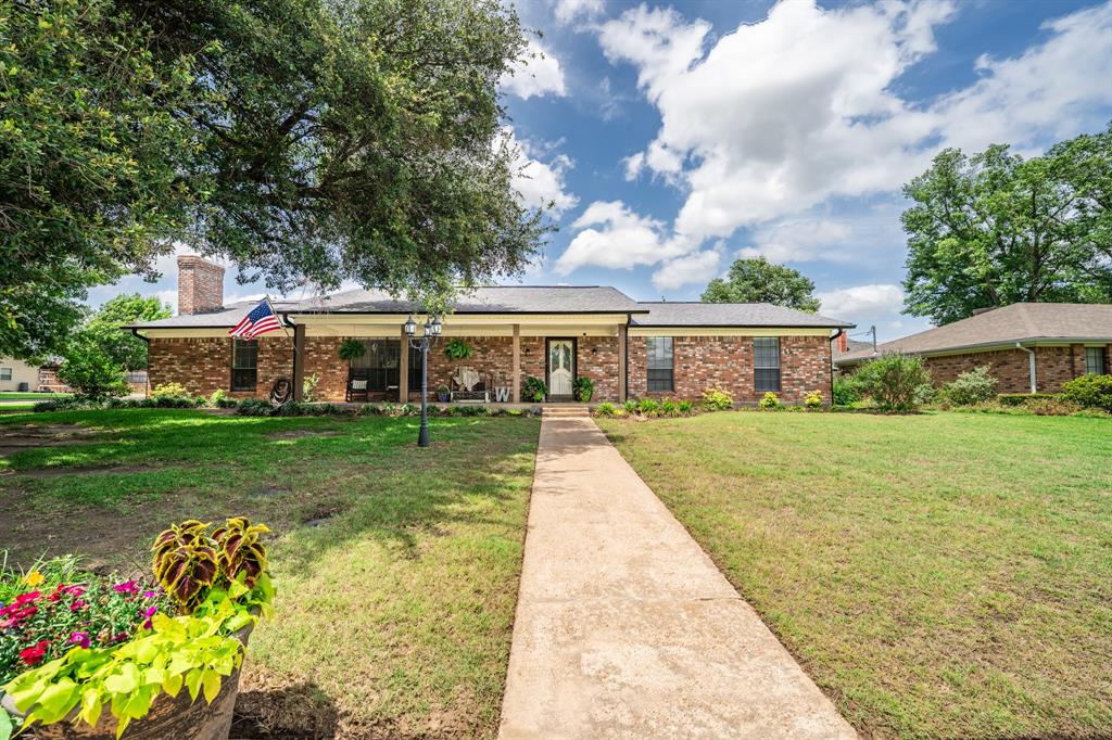 Spacious updated 5-bedroom home that can easily be used as a 6-bedroom, is found in the heart of southern Sulphur Springs! Located in a desirable neighborhood with mature trees, the brick house has a flexible floor plan for the whole family. Make an impression with the farmhouse chic entryway that leads to the large main living room with a brick wood-burning fireplace. A second living area with a fireplace can also be used as a mother-in-law suite, office, play room or flex space. The large kitchen provides plenty of space with stainless steel appliances and butcher block countertops. Light luxury vinyl plank flooring brightens up all the living and dining areas. The primary suite gives you the ultimate retreat with an updated bathroom and spacious bedroom. Enjoy the fenced backyard with a covered back patio. All of this located on a corner lot in Green Acres and zoned for the brand new Rowena Johnson Elementary.