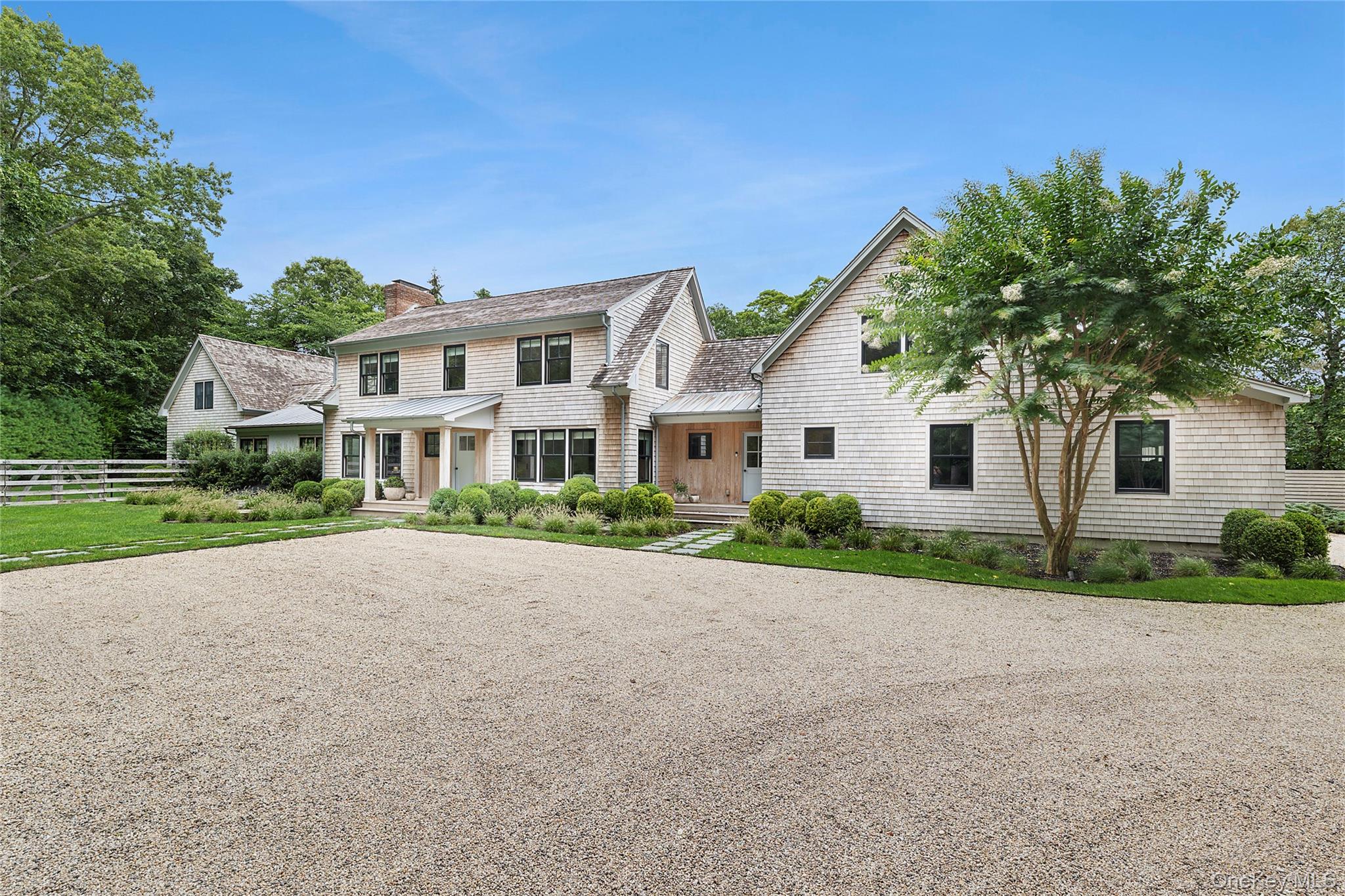 On a quiet cul-de-sac just moments away from East Hampton Village and ocean beach, this interior designer's own residence has been thoughtfully reimagined with updates that blend modern sophistication and timeless comfort. Every detail reflects a curated eye for design, elevating both style and livability. The home is organized into three distinct sections-perfect for both entertaining and retreat. The central entry opens to light-filled living spaces featuring wide plank pickled pine flooring and airy proportions. A family room with wood-burning fireplace flows seamlessly into the chef's kitchen, outfitted with marble countertops, waterfall island, Wolf and Sub-Zero appliances, and sleek custom cabinetry. The dining room and additional living room with fireplace extend the open feel, with all three spaces connecting to the patio and pool through glass doors. The primary wing offers a serene primary suite with vaulted ceilings, skylight, walk-through closet, and spa bath with soaking tub, frameless glass shower, and double vanity. A sauna completes the suite. Upstairs, a private guest suite provides comfort and seclusion. The second floor is complete with three additional bedrooms, among them an en-suite featuring designer barn doors and a custom bath. Off the kitchen, there is a full bath, mudroom, laundry, and access to the 2-car garage. Above the garage, a spacious studio currently serves as a recreation lounge with custom banquettes. Outdoors, the property is framed by beautifully landscaped grounds with mature trees, ornamental plantings, and seasonal gardens that create a sense of seclusion. A scenic easement along two sides of the lot further enhances privacy, ensuring uninterrupted enjoyment of the bluestone patio, outdoor living and dining areas with fireplace, heated gunite pool and spa, pool house with kitchenette and automatic door, plus an outdoor shower and changing area. This home embodies the best of Hamptons living-a designer's vision realized in a tranquil yet convenient location.