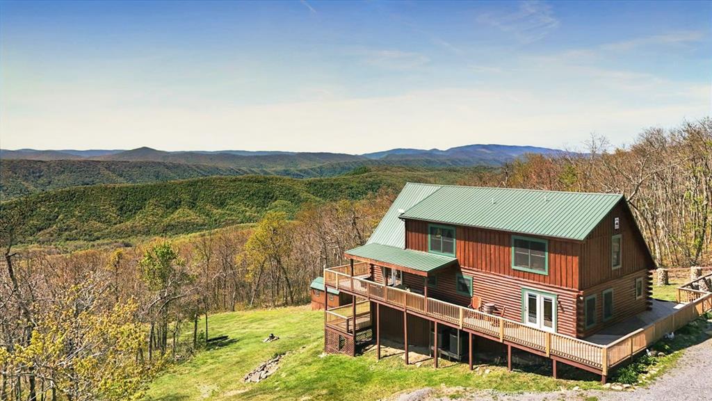 Stunning panoramic views of the Appalachian Mountain region which include East River, Blue Ridge, Alleghany and Jefferson National Forrest! You will experience this and so much more when escaping to this mountain top getaway featuring a 3 BR, 2.5 BA log style home on 17 acres! Unplug, unwind and embrace the open skies from all directions. This Gatlinburg style log home is referred to as "Big Bear Lodge" by the current owners. The style is defined by casual, comfortable and has rustic aesthetic. There are beautiful night skies and no neighbors in sight. This home offers both open and covered decking wrapped around the entire home for your enjoyment. Even the 2-car detached garage has a side deck. Upon entering the home, you will find an open floor plan including the living room, kitchen and dining area. The "WOW" factor is the floor to ceiling windows that allow you to experience outdoor nature during all four seasons, no matter the weather conditions! The kitchen features custom cabinets with unique wood working designs created by the current owner. The primary bedroom with a free-standing gas fireplace and ensuite bath is on the main level, as is a large laundry room with closet and pantry. The custom staircase leads to an upper-level open loft, 2 additional bedrooms and full bath. The basement offers excellent storage or could be finished for additional living space. If you are considering an investment for a second home for your family or wish to purchase property for AIRBNB use, then this property is perfectly packaged for both! Located in a gated community.