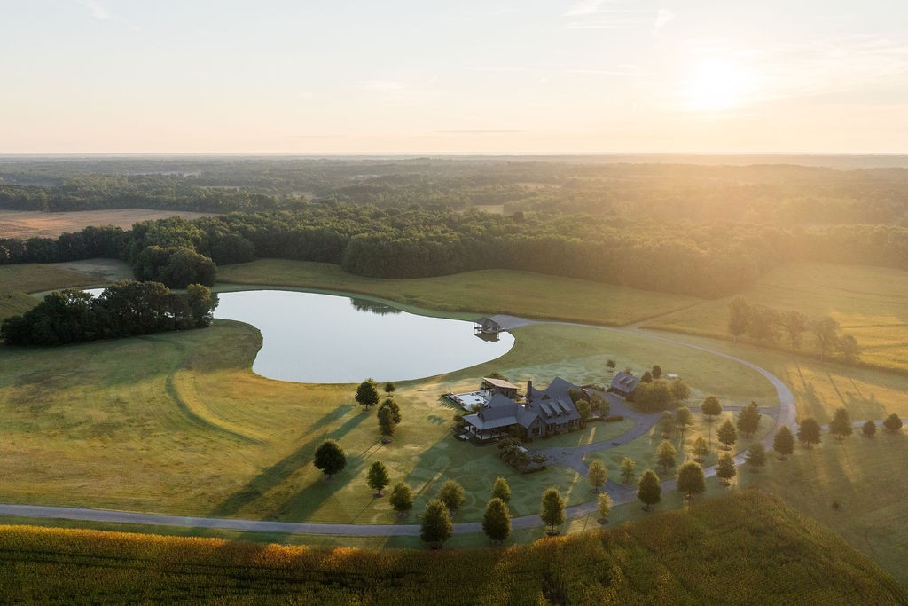 Spanning nearly 2,500 acres, Pitchfork Farm is one of the most significant farm and estate offerings in the Mid-South. Established in 2009, the property combines large-scale agricultural productivity with refined country living, anchored by a 10,036 sq ft custom residence overlooking a spectacular 6-acre lake with two slip dock.  At the heart of the main level you’ll find a professionally designed chef’s kitchen featuring dual Sub-Zero refrigerators, Wolf appliances, a butler’s pantry and a striking custom zinc island. Multiple large open living spaces flow seamlessly to expansive covered porches. These outdoor spaces are thoughtfully equipped with fireplaces, overhead heaters, and integrated AV, creating a refined atmosphere for year-round indoor-outdoor living. basement is purpose-built for entertaining, featuring a five-queen bunkroom with private sleeping pods, a theater room, AV room, full wet bar, and a 1,200-bottle temperature-controlled wine cellar. The property’s landscape is enhanced by three ponds, one of which is the 6-acre lake directly below the residence. The home, pool, and outdoor terraces command unobstructed views across the water, offering a serene backdrop for both daily living and large-scale entertaining. The farming operation consists of two main divisions: a small square hay enterprise and a row crop business. The farm has a substantial headquarters consisting of an office, two shops, one of which has a three-bedroom guest quarters above, and covered equipment parking. All farming equipment remains, and the current farm staff would like to continue working for the new owner making the farm completely turnkey. Additional farmhouse located on property for farm manager. The farm has 7.7 miles of internal roads of which 1 mile is asphalt from the farms entrance to the residence. This exceptional custom estate blends timeless sophistication with modern functionality, offering a rare opportunity for luxurious living and effortless entertaining