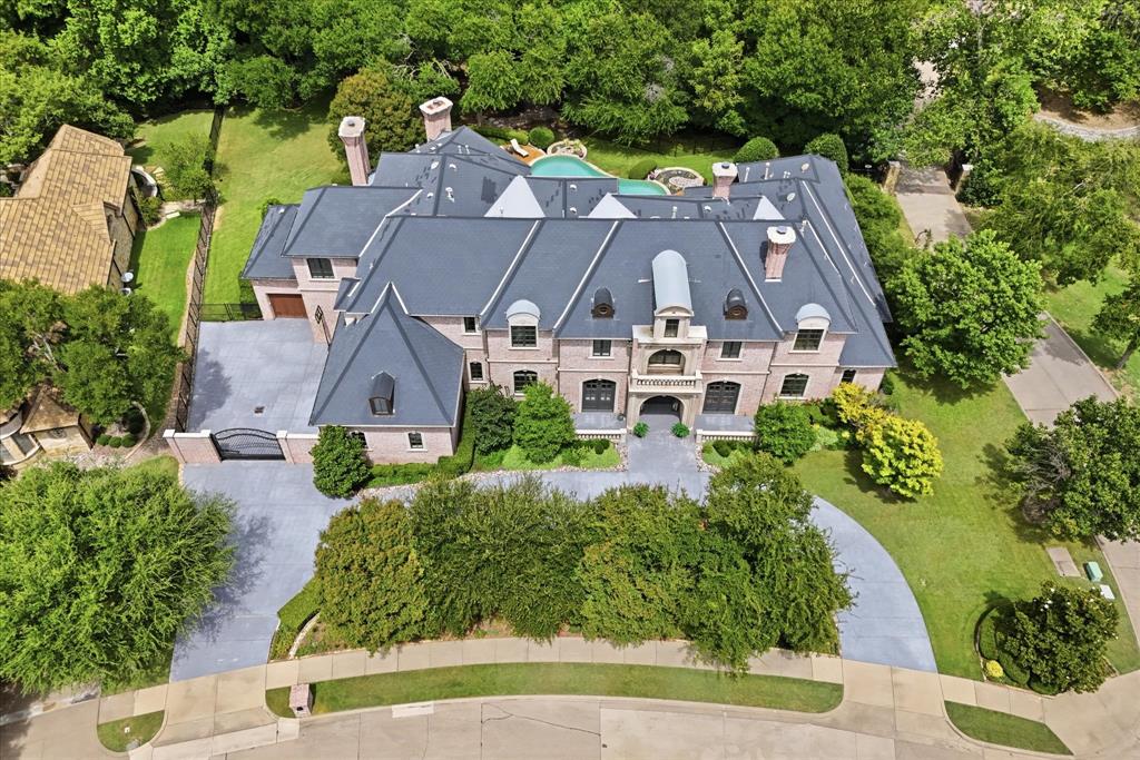 Beautifully crafted French-inspired estate on a private, heavily treed .74 acre creek lot in the exclusive gated and guarded community of King's Gate, an intimate enclave of fewer than 50 homes on estate tree lined lots. Walls of floor to ceiling windows showcase breathtaking views of the resort style pool, spa, outdoor entertaining areas, and tranquil creek, creating a true private retreat. Designed for both grand entertaining and daily living, this exceptional floor plan offers remarkable flexibility with two Primary Suites on the first floor, one currently serving as a private Study, plus a spectacular two-story Library with built-ins, spiral staircase, loft, and adjoining Art and Fitness Rooms. The dramatic Living Room features soaring ceilings, a floating staircase, and a cast stone fireplace, while the renovated Chef's Kitchen impresses with custom cabinetry, designer countertops, dual pantries, prep island, Wolf professional appliances, and exceptional workspace. Additional first-floor highlights include a Media Room, wine room, multiple entertaining bars, and elegant Butler's Pantry. The luxurious Primary Suite offers a fireplace, sitting area, coffee bar, separate His and Her baths with oversized walk-in closets, and a shared spa inspired shower, a separate stairway takes you to the private Fitness Room, Art Room, half bath & walk-in cedar closet. Upstairs, on the other side of the home, offers an expansive Game Room with kitchenette, wet bar, balcony, and three oversized Bedroom Suites, each with private bath and walk-in closet. Ideally located near the Dallas North Tollway and SH 121 with convenient access to Legacy West, Grandscape, The Star, premier shopping, dining, and entertainment, this extraordinary estate combines timeless craftsmanship, unmatched privacy, and exceptional convenience in one of North Texas' most exclusive communities. With these views, you will feel like you are on vacation every day.