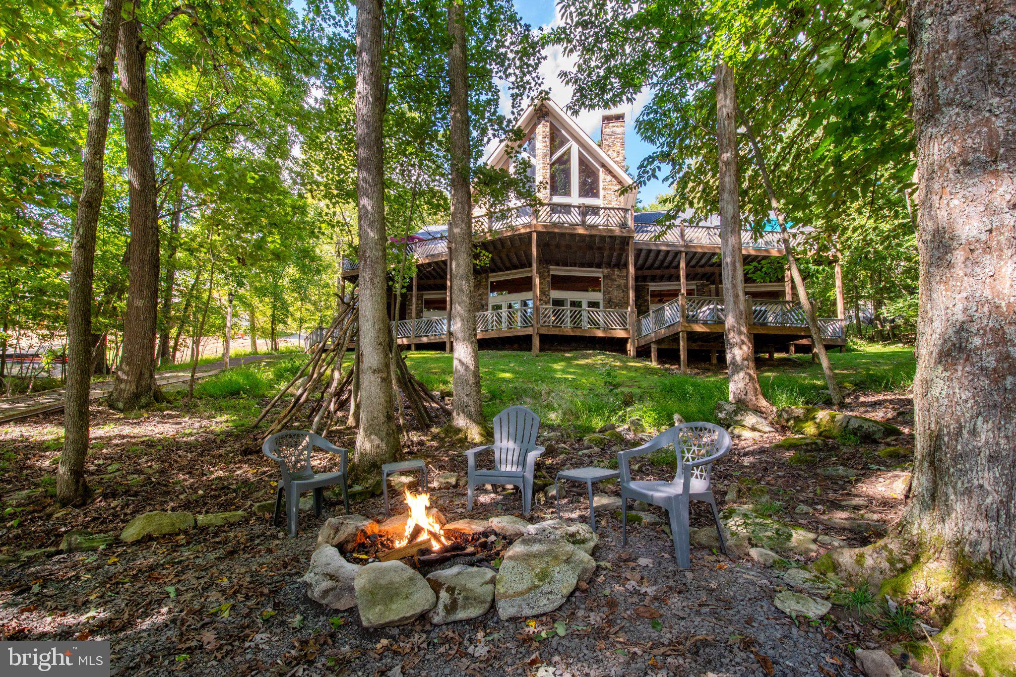 Stunning lakefront living awaits at this exceptional Deep Creek Lake retreat, offering 65 feet of prime waterfront, a private Type A dock, and a coveted minimal-wake cove. Designed to embrace the lake lifestyle, the expansive deck and dock enjoy full-day sunshine—perfect for boating, swimming, relaxing, and entertaining from morning through sunset.  Inside, custom finishes, wide-plank wood floors, and two massive stone wood-burning fireplaces create a warm and sophisticated mountain-lake ambiance. The thoughtfully designed open-concept kitchen, dining, and great room provide an inviting gathering space for everyone. The chef’s gourmet kitchen features an abundance of workspace, three sinks, and a comfortable layout ideal for both everyday living and entertaining. The large eat-in bar adds another fun and distinctive gathering spot. One more thoughtful feature is the pet shower, right off the mudroom and two-car attached garage.  With 6 bedrooms and 5½ baths, there is plenty of room for family and friends. And if overflow sleeping is needed, there is a sizeable upper level loft that also doubles as a great play/gaming area that the kids will love! The lower level is truly impressive, featuring 12-foot ceilings, generous living space, and sliders that walk-out to an expansive patio, hot tub deck, and fire pit. Two large decks extend the living space outdoors and offer multiple areas to enjoy the beautiful lake setting. Your family will never be bored here – from the lake, hot tub, game tables, fireplaces, playroom, and tennis court, your guests have many options for entertainment. The private tennis court could easily be converted to include pickleball and basketball and function as a sports court, with a storage shed and gazebo right beside.  Situated at the end of the road, this property offers a peaceful, private setting with excellent opportunities for walking and hiking right from the home. From the sun-drenched canopy dock fit for two boats and minimal-wake cove to the expansive gathering spaces and custom craftsmanship, this is a remarkable Deep Creek Lake property designed for making memories year after year. Established vacation rental with impressive annual income “Fair Oaks on the Cove”.