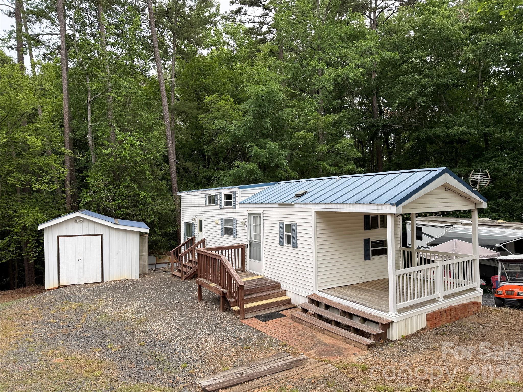 Well this unit is just fun. 2008 Park Model with 2 bedrooms, 2 bathrooms and double lofts. An additional 12' of common area was purchased, making it perfect for the full addition. The lot backs up to woods so there will never be anything behind you. There is a covered front porch for waving at folks and watching the golf carts go by.  Full size appliances to remain. Washer/dryer in out building to remain. Taller ceilings in the living room and dining area. Both bedrooms are of good size. Primary bedroom is 2 steps down and has a queen bed. The other bedroom has a double on bottom and a single on top. Both bathrooms have step in showers.  Close to the heart of the park and the church. This one comes furnished. Come and see if this could be your "Happy Place" here in the park. This park model has 2 entrys/exits. The propane tank to the gas pack HVAC was rented and return to propane company for lack of use in the winter. Seller states heat worked well when they removed the propane tank.All buyer's must be with a realtor to gain entry to the community.