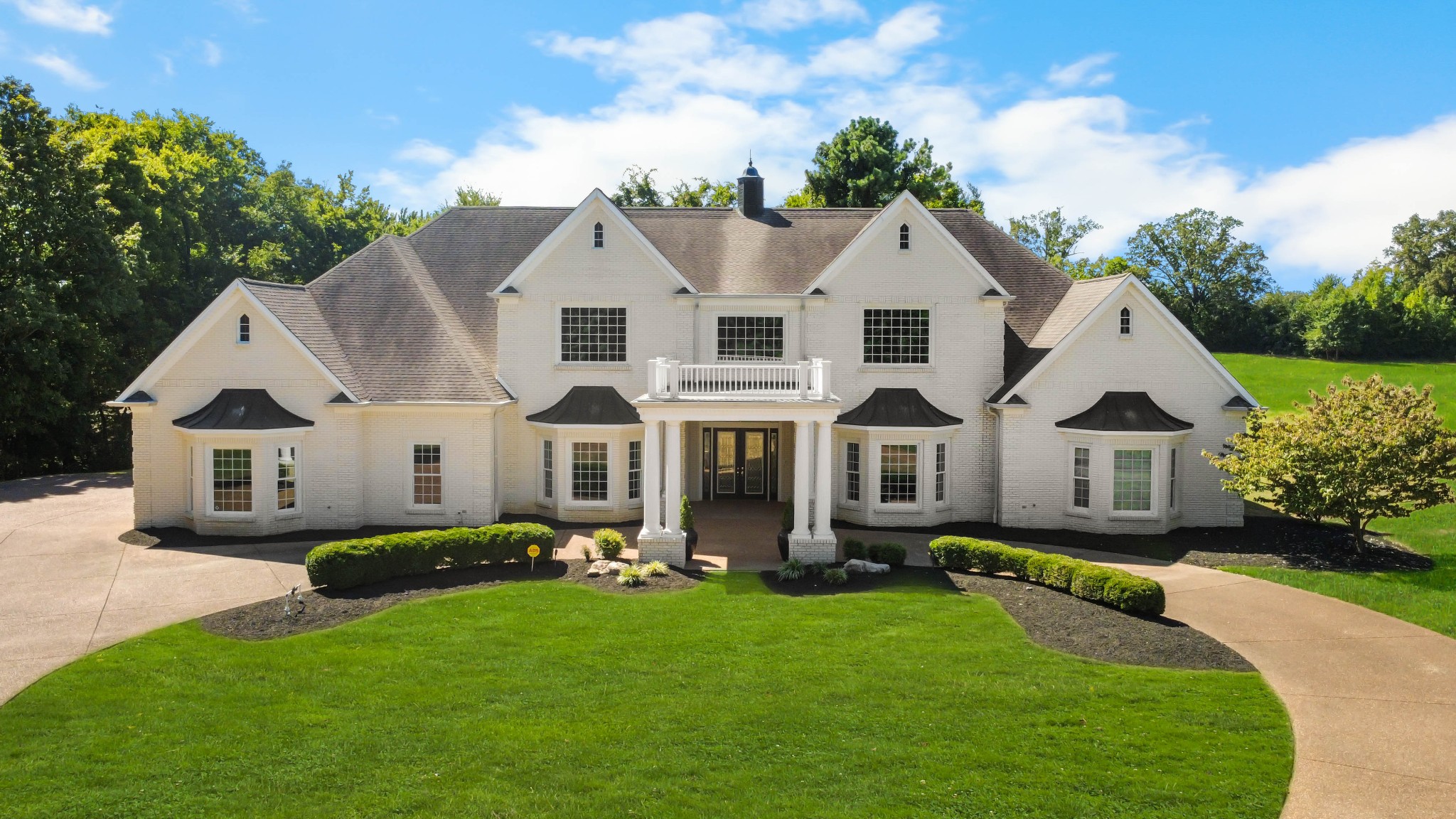 Stunning and stately, this impressive 8,300 sq. ft. residence sits gracefully on 1.88 acres, reached by a picturesque tree-lined driveway and highlighted by a grand porte-cochère. Every detail of this home exudes sophistication and comfort. Inside, the welcoming foyer opens to formal and casual living spaces, including a formal dining room and a beautifully designed eat-in kitchen featuring double islands, an abundance of custom cabinetry, a butler’s pantry, and stainless steel appliances—perfect for entertaining.

The oversized primary suite is a true retreat, offering an expansive en-suite bathroom, a massive walk-in closet with built-ins, and an attached fitness room for ultimate convenience. The thoughtful floor plan includes a dedicated office for remote work, a charming Florida room filled with natural light, and a tornado shelter for added peace of mind.

Elegant details are found throughout—from coffered ceilings and intricate trim work to the seamless flow between rooms. Outdoor living is equally impressive with an open patio overlooking the manicured grounds, complete with an irrigation system to maintain the lush landscape. Additional highlights include 3 spacious bedrooms, two and a half bathrooms, a three-car garage, and refined finishes that elevate this home’s timeless appeal.

Combining luxury, comfort, and functionality, this remarkable estate delivers an unmatched lifestyle in an exquisite setting.