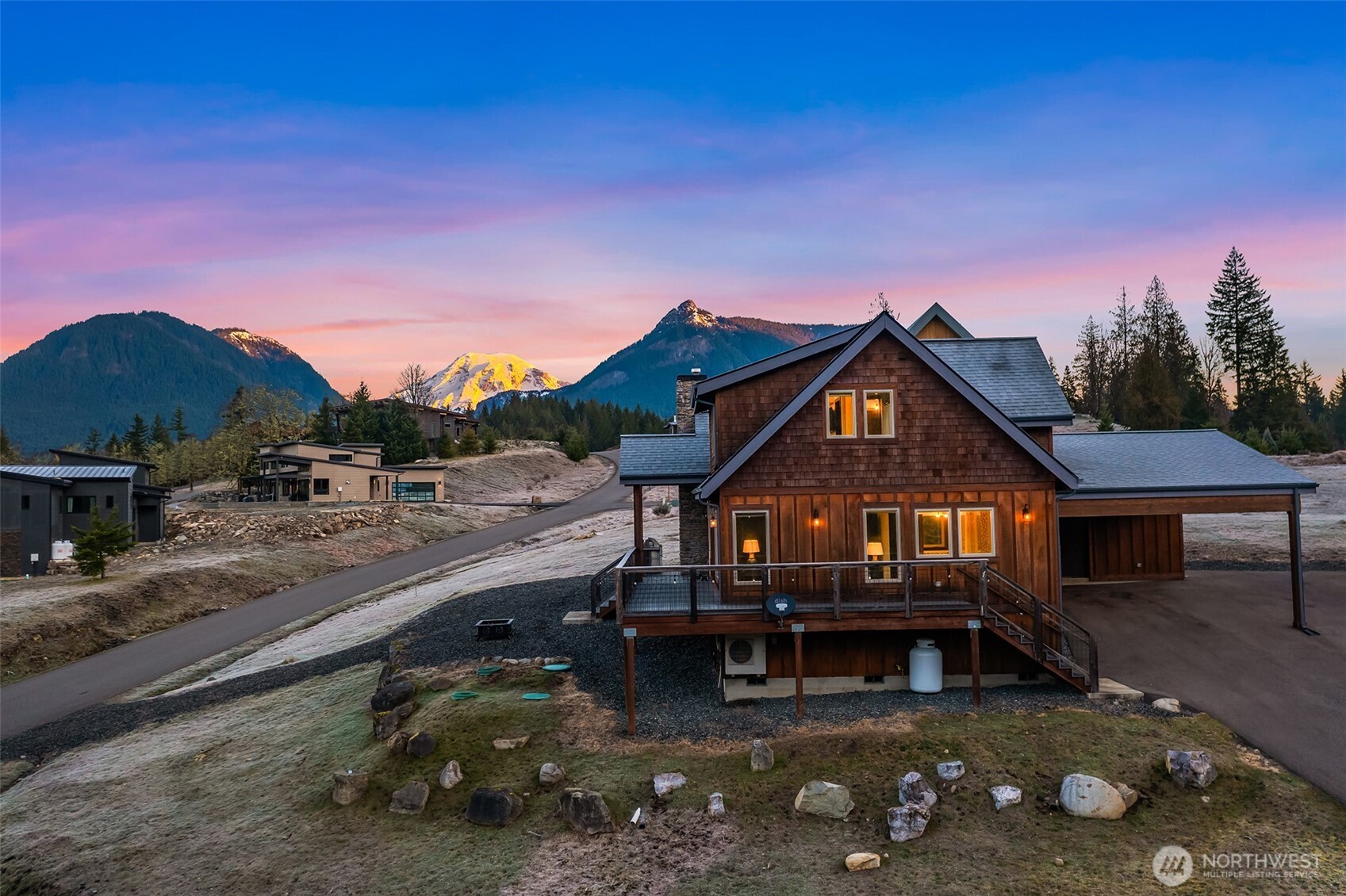 Welcome to Hideaway, Packwood’s premier gated neighborhood with arguably the best Mt. Rainier view in town. Sitting proudly on a shy half-acre is this stunning 2019 chalet. It features a NanaWall of glass facing the spectacular Mt. Rainier view, creating a seamless indoor-outdoor flow on to the composite low-maintenance wrap-around deck. The main level open-concept great room showcases a floor-to-ceiling fireplace that warms the room with the flip of a switch. The kitchen is equipped with a Dacor gas range and matching stainless-steel appliances. A hammered apron-front copper sink serves as a striking focal point, pairing beautifully with the granite countertops. Don’t miss the wet bar with wine fridge and matching hammered copper sink. The primary suite offers another gas fireplace and a 5-piece bath with clawfoot tub. Upstairs, you’ll love the bunk room with west-facing Cowlitz River Valley views. The third bedroom is adjoined by another full bath. The exterior is clad in cedar shake and stained board and batten siding, establishing a timeless aesthetic. The freshly paved asphalt drive welcomes you to the attached two vehicle carport with a beautiful tongue and groove ceiling and a convenient sizeable storage room for your recreational gear. Less than a mile from the shopping, dining, and entertainment of Packwood’s town center and 25 minutes from White Pass and Mt. Rainier National Park, this durable and timeless chalet is offered furnished for your immediate enjoyment.