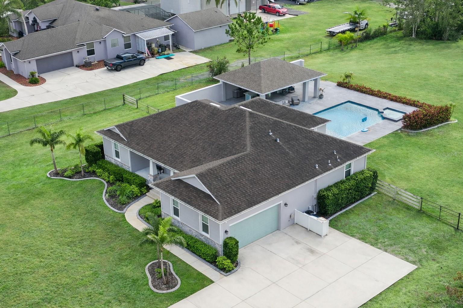 Welcome to Bay Lake Ranch, where spacious living meets a vibrant sense of community. This custom-built home is set on 2.9 acres, offering both privacy and room to enjoy the outdoors. The property features a flexible floor plan with three bedrooms and three bathrooms, plus a fourth room with a closet—ideal as an additional bedroom, office, nursery, or creative space.Step outside to a large pool and hot tub surrounded by a generous pool deck, perfect for gatherings or relaxation. The outdoor kitchen is fully equipped with a bar and ample seating, making it easy to entertain. For those with hobbies or storage needs, a 2,300-square-foot, two-bay metal building with a concrete pad and extra covered parking provides plenty of options. There’s also a pole barn with space for four vehicles or trailers of any size, and the land behind the home is securely fenced.Manicured landscaping surrounds the home and pool, creating a welcoming outdoor environment. Inside, stained concrete floors offer durability and low maintenance throughout. High ceilings and recessed lighting enhance the open feel, while the kitchen stands out with staggered cabinetry, crown moulding, and solid surface counters. Crown moulding continues throughout the home, adding a polished finish.The sunroom offers views of the pool and features large sliding glass doors that can be opened to create a seamless indoor-outdoor living experience. Custom finishes are found in every corner, reflecting thoughtful design and quality craftsmanship.Bay Lake Ranch is known for its large lots, custom homes, and community spirit, with annual events—like the popular Halloween celebration—bringing neighbors together and attracting visitors from beyond the neighborhood.