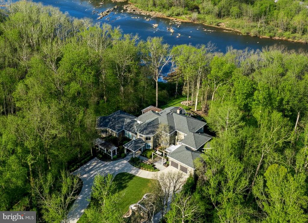 Commanding an incomparable vantage point above the Potomac River, this extraordinary stone estate by BOWA defines timeless sophistication and total privacy on more than three gated acres in McLean’s most coveted enclave, moments from Washington, D.C.Beyond its stately approach and manicured grounds, the residence reveals  16,000 square feet of refined interiors designed for both grand entertaining and serene daily living. A two-story great room with floor-to-ceiling windows frames sweeping river views, while French doors open to an expansive terrace that captures the tranquil beauty of the surroundings.The gourmet kitchen is a showpiece with professional-grade appliances, granite surfaces, a walk-in pantry with Sub-Zero refrigerator, and a hidden bar. The main level also offers dual offices, two powder rooms, elevator access, and a full laundry with pet bath—all under soaring ceilings that enhance light and volume.The main-level owner’s suite is a private sanctuary with windows on three sides, dual dressing rooms, and a marble spa bath with jetted tub, steam shower, and private balcony overlooking the river. Upstairs, three guest suites each feature walk-in closets and elegant baths, two with French doors to balconies.The lower level is a destination in itself—featuring a lounge with stone fireplace, billiards area, wet bar, wine cellar, fitness room, and a stunning indoor pool with skylights and glass doors opening to extensive stone patios. Additional amenities include a private in-law or staff suite with full kitchen, a salon, guest suite, and generous storage.Outside, terraced gardens, pergolas, water features, and a gazebo with full outdoor kitchen create a breathtaking resort-style setting. With five-car garage parking, geothermal systems, and whole-house generator, this distinguished estate offers rare scale, craftsmanship, and uninterrupted Potomac River views.