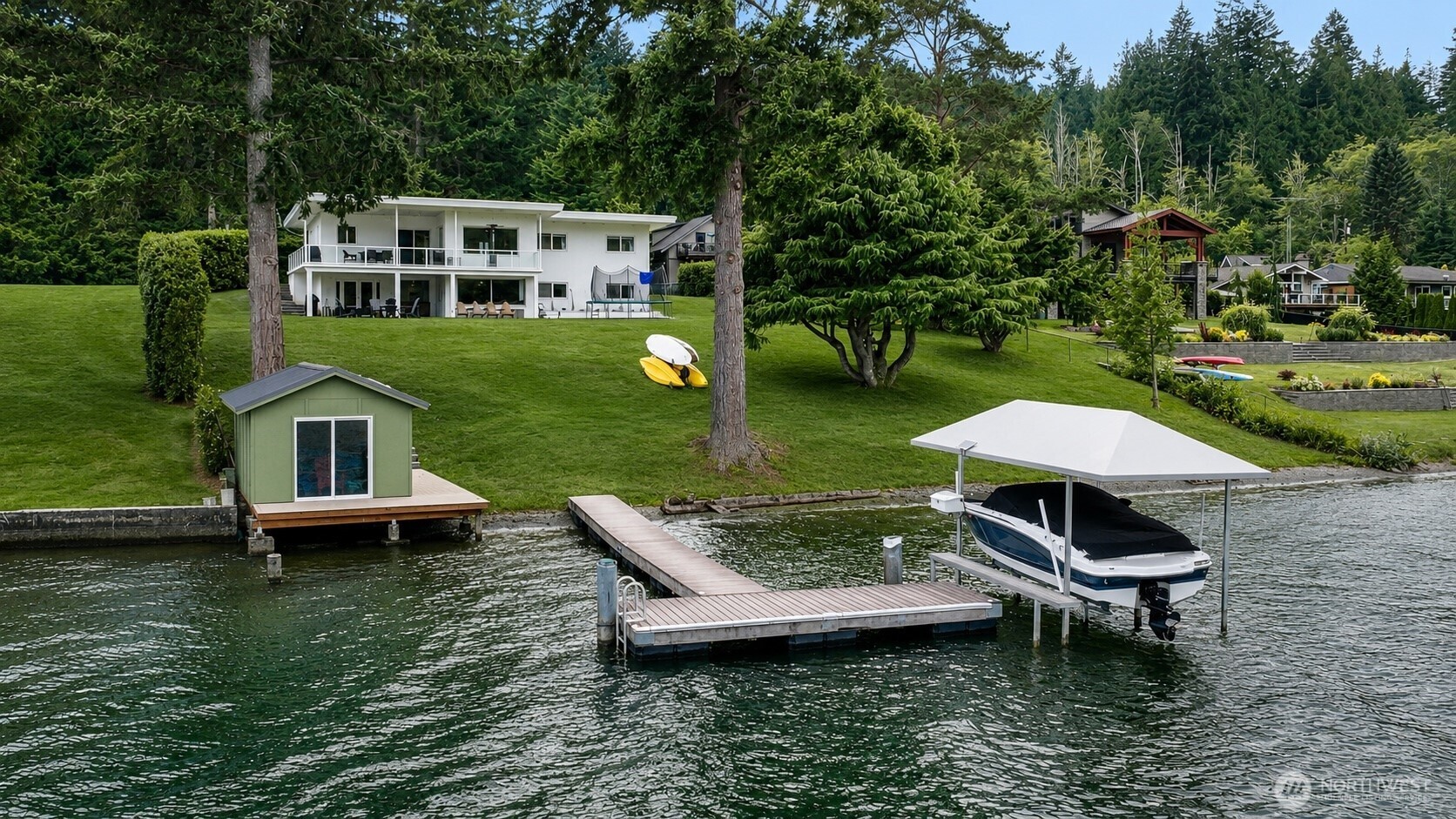 Tucked along 120 feet of low-bank shoreline, this 1.1-acre waterfront property is defined by its easy connection to the water, peaceful surroundings, and a level of privacy that is increasingly rare to find on the lake. A gently sloping lawn extends to the shoreline, where a private dock and a rarely available boathouse make it easy to spend the day on the water.The home was extensively renovated in 2018, including a complete interior remodel and a new electrical panel. Additional updates include air conditioning, a new garage door, and an electric vehicle charger. A detached shop and additional outbuilding provide ample space for projects, storage, or recreational equipment. The lower level features its own entrance, offering flexible space for guests, extended living, or a variety of other uses. Whether you're looking for a full-time residence or a quiet waterfront retreat, the setting is what truly sets this property apart.