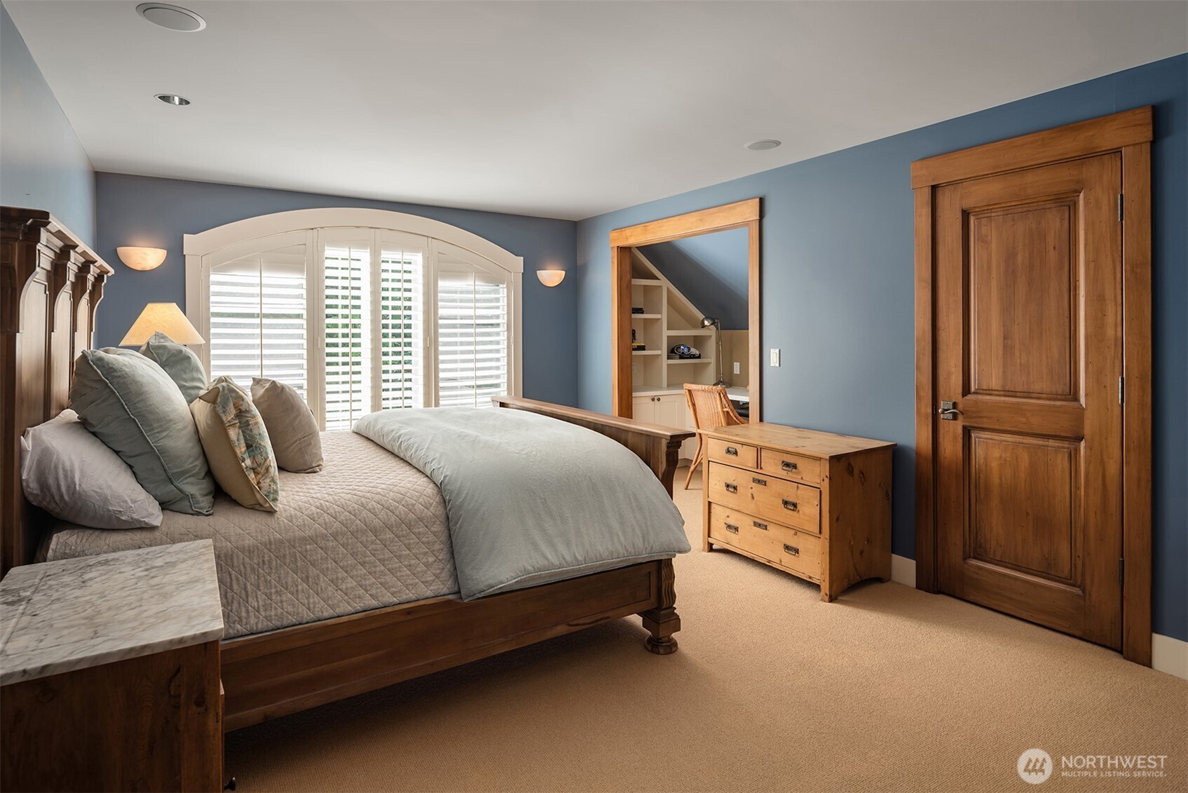 Blue bedroom with wood bed frame and built-in desk nook