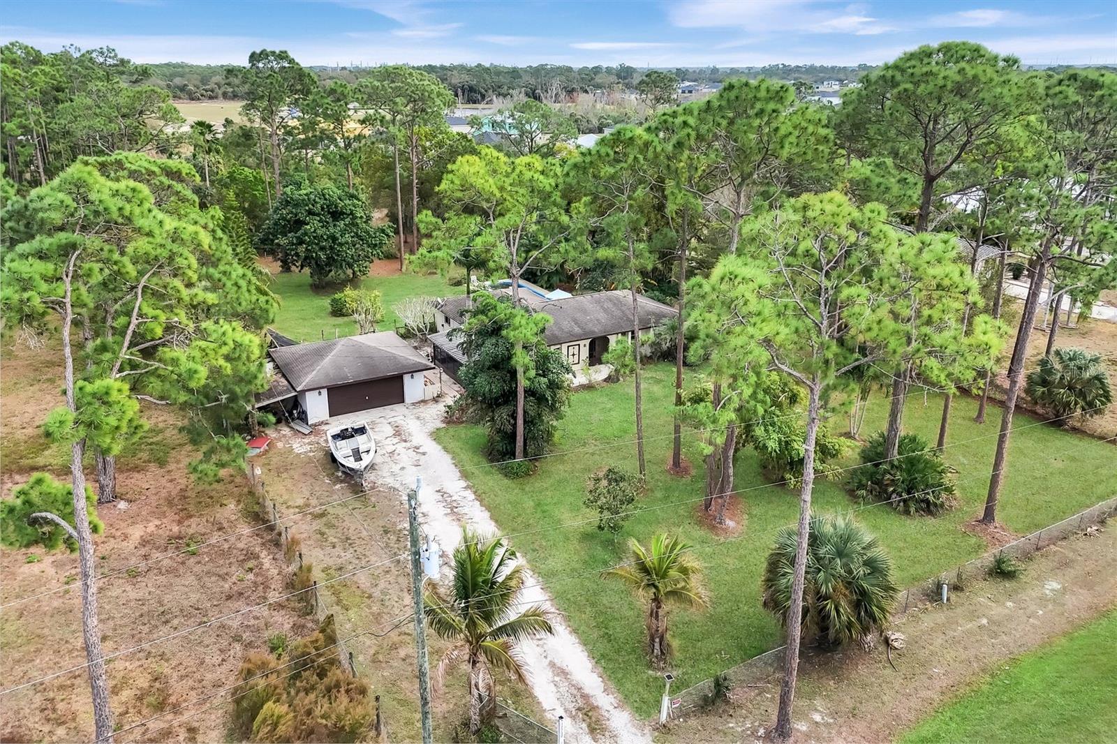 1+ ACRE, AG-2, 3/2/2 POOL HOME CLOSE TO 75! Set on approximately 1.10 acres in unincorporated North Fort Myers, this property offers a rare opportunity to own a private, tree-canopied homesite with an established tropical landscape that took decades to create. The land is the star here, providing exceptional privacy, shade, and a true Old Florida setting—surrounded by newer development yet distinctly peaceful. Home features 3 bedrooms, 2 baths with 1816 sqft under air and a detached garage. Inside has tile through out, kitchen with updated counters, vaulted ceilings and more! The backyard is densely planted with mature, income-producing fruit trees, including Valencia Pride mango (known for exceptional fruit), avocado, bananas, pineapples, oranges, carambola, key lime, and Meyer lemon, along with extensive ornamental plantings. Flowering varieties such as magnolia, gardenia, plumeria, hibiscus, roses, bougainvillea, star jasmine, night-blooming cereus, goldenrain tree, and sapphire showers duranta create year-round color and fragrance. Towering 50-foot+ pines, Norfolk pine, mahogany, and multiple palms—including royal palm, travelers palm, fishtail palm, ponytail palm, pygmy date palms, and mini coconut palms—complete the layered landscape, accented by crotons, ixoras, and staghorn ferns. Home is positioned comfortably within the lot and offers functional living today with flexibility for future improvements and/or expansion - just bring your imagination! Relax on the back porch overlooking a fully functional fiberglass pool, ready for use. A large screened lanai, detached garage, long driveway, and fully fenced lot provide space for pets, RV, boat storage, animals, or recreational toys—NO HOA. Located in Flood Zone X - This property has NEVER flooded and performed well through every hurricane since 1983. Enjoy acreage living with privacy, mature trees, and SERIOUS potential—just minutes to I-75 for an easy commute. A rare opportunity to own land, space, and long-term flexibility in a rapidly changing area. Home needs some work so get ready to roll up your sleeves and make it YOURS!