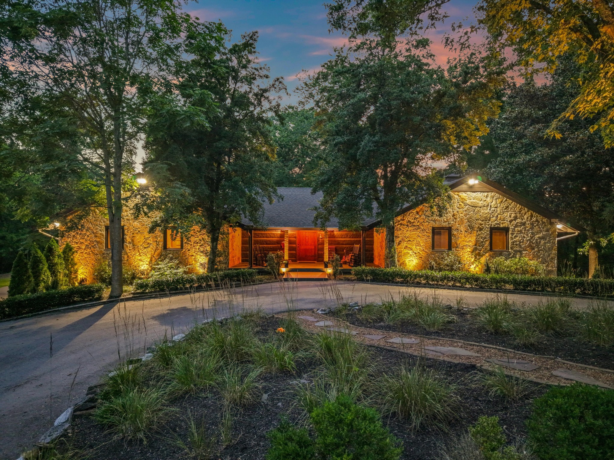 Just minutes from Leipers Fork Village, this extraordinary 41.5-acre gated estate, with two ponds, redefines what it means to live stylishly in the country. Hidden and private behind gates, a winding half-mile paved drive through pastures and native hardwoods makes this property feel worlds away—yet it’s close to everything that makes Leipers Fork iconic. At the top of the ridge sits a masterfully renovated, hand-hewn log and stone home—equal parts artistic and sophisticated. Every inch of this residence has been elevated with artful design, moody textures, and modern comfort. The home features a generous front porch, two stone fireplaces, open living spaces and a chef’s kitchen built for gathering. The primary suite and two additional bedrooms are set apart from the public spaces for privacy, and a large bonus room, currently used as a music studio, could make ideal guest quarters. The enclosed climate controlled sun porch is something to be experienced, with doors opening out to your own private wellness retreat— complete with a hot tub, sauna, and cold plunge overlooking the trees. 
Just beyond, a fully renovated, climate-controlled barn, currently a gym and guest space, features a wet bar, full bathroom with laundry, ground-floor flex room, as well as a sleeping loft. From there, a short path leads a ridgetop swimming pool with a custom container bar, ideal for epic entertaining. The pool sits adjacent to the 5-6 bedroom perc site, making an ideal situation if someone desires to add a larger home to the property. Outdoors, the over 41 acres of land unfolds in a mix of rolling pasture, two stocked ponds, mature woods, and an antique hay barn that nods to the property’s history. With two approved perc sites, the opportunity for expansion is yours. Whether you’re seeking a refined country compound, a wellness-inspired sanctuary, or an entertainer’s dream setting surrounded by natural beauty—this is one of the most captivating properties in Leipers Fork.