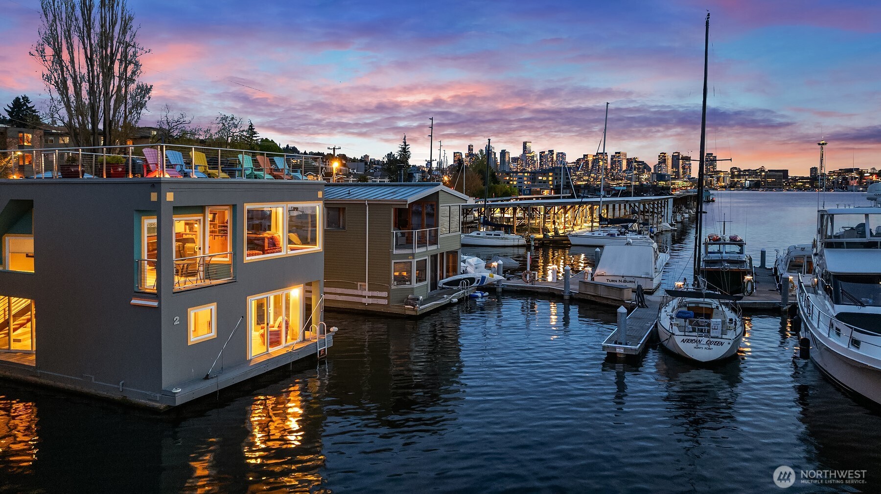 Front-row Roanoke Reef | Stunning west-facing open-water views: Space Needle, Queen Anne, Gas Works, Olympics | 2BR/2.5BA architecturally-designed | 2 secure EV-charged garage parking + storage | 2 boat moorage slips. There are waterfront homes in Seattle, and then there's the front row of Roanoke Reef. The Space Needle and Queen Anne Hill rise to the southwest, the Aurora Bridge arcs over the Ship Canal to the west, Gas Works Park sits directly across the water — a 180-degree panorama from the living room of this floating home at the head of a gated condo-owned dock. The primary suite on the water-level floor features a built-in king captain's bed, walk-in California Closet, and sliding glass doors to two boat slips. A second bedroom has custom twin XL Murphy beds and en-suite bath. A utility room with workbench, laundry & storage opens to a boat deck. Connected via a sculptural floating staircase, the upstairs opens into the view. A living room with gas fireplace, built-in two-person office, and drop-down movie screen. A full-sized updated kitchen with built-in oven, bathed in natural light, flows into an open-view dining room that seats 8+. A full-size staircase—wide enough to carry trays & platters—climbs from the kitchen to a large rooftop deck surrounded by endless Seattle views. Day by day, float planes come & go, commercial ships work the Ship Canal, sightseeing boats & yachts cruise by, sailboats chase the wind. Year-round, the lake provides a never-ending show.