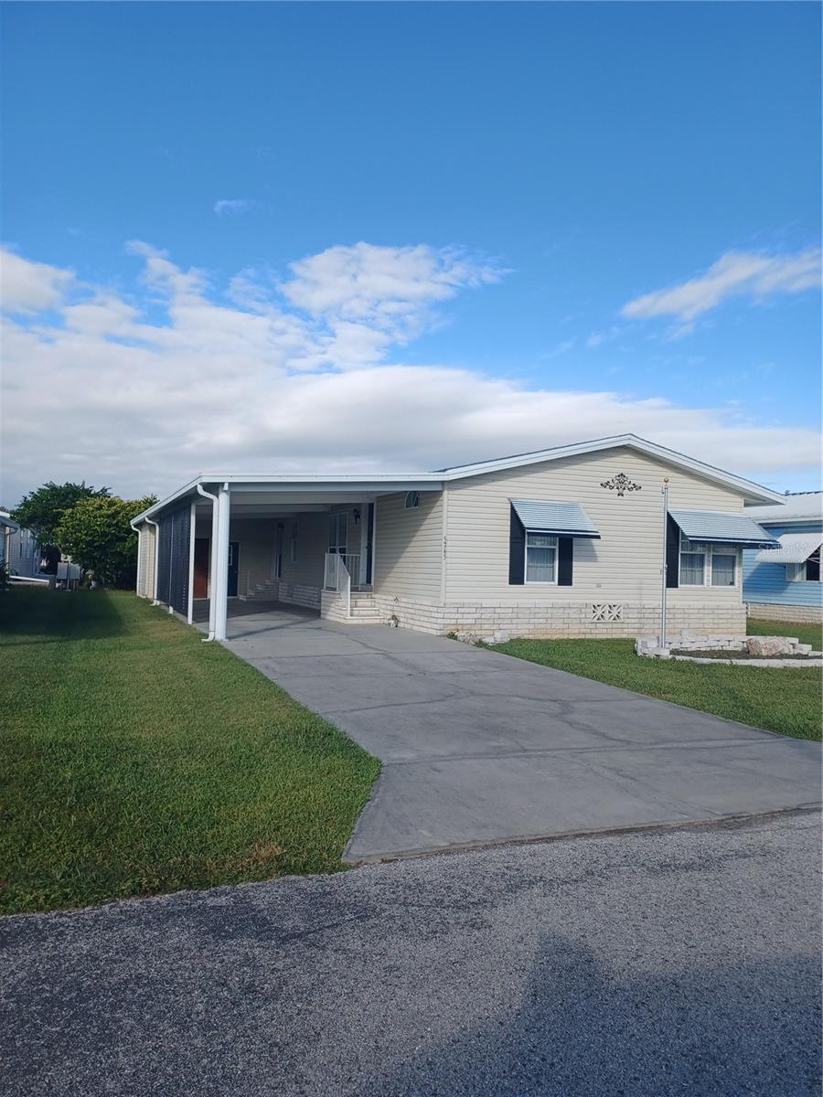 Own your own land in this 55+ community centrally located between Orlando and the Gulf Beaches. This home is spacious so you can accommodate your out-of-town guests. As you enter into the home and step into the kitchen you will feel right at home. The kitchen island has a sink and under counter dishwasher. The stainless-steel appliances, white cabinets and pantry compliment the kitchen. At the front of the home is a set of glass doors that open to an office with beautiful laminate flooring and a window to let in the morning sun. The study/den is carpeted with plenty of windows to sit and relax with a great book. On the other side of the hallway just past the full-size bathroom and linen closet is the 2nd bedroom with reach in closet. On the opposite end of the home is a Livingroom/dining combo with beautiful laminate flooring and an accent wall in the living room. A doorway from the Livingroom leads to the Primary bedroom with laminate flooring and a walk-in closet. Get away from it all when you step into the Primary Bathroom. Your eyes will immediately be drawn to the claw foot tub and notice the roominess of this bathroom where you can relax with a beverage of your choice(!) or are you more of a shower person? Then you can step into a custom designed shower with special lighting and even music. The door from the dining room leads to the laundry/mudroom complete with washer and dryer, cabinets above the washer and dryer and a closet for extra storage. The other doorway leads to the outdoor covered area where you can create your outdoor cozy space. The roll up door is for additional storage, or you might want to park a golfcart (for the ride around the community). All windows throughout are double pane and have vertical blinds. All "wet areas" throughout the home are tiled. The exterior of the home has louvered awning. The ANNUAL dues are $435. There are many amenities available for an additional fee such as golf, swimming/hot tub, tennis, shuffleboard, racket and pickle ball, 3 clubhouses, game room and library just to name a few. Some amenities are low or no cost. Ride your golf cart around the community or walk the sidewalk around the lake on those beautiful evenings.