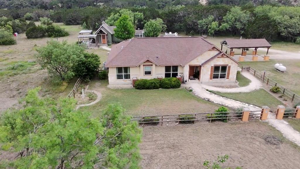 Welcome to The Evensong Retreat nestled in the heart of Concan, Texas! This charming three-bedroom, two-bathroom home is perfectly set on over 6 peaceful acres of rolling Hill Country terrain. Designed with timeless country styling and modern comfort in mind, the home features a spacious open-concept layout, raised ceilings, and rustic finishes throughout. Large windows fill the space with natural light and offer serene views of the surrounding oak-dotted landscape. The main house offers cozy, well-appointed bedrooms, a large living area perfect for family gatherings, and a modern farmhouse-style kitchen with ample storage and stainless-steel appliances. Outdoors, the large back porch invites you to relax with a morning coffee or evening drink while watching the wildlife wander through the trees. Adding to the property's appeal is a fully separated and highly successful Airbnb or guest house—ideal for generating income or hosting friends and family. Tastefully decorated and comfortably equipped, it offers privacy, its own entrance, and a proven rental history. A large barn offers storage, workspace, or potential for hobby farming, while the beautifully designed chicken coop—both practical and stylish—brings a touch of whimsy and function for those dreaming of fresh eggs and country living. Tucked away near the seasonal dry creek is a serene private chapel, perfect for reflection, intimate gatherings, or simply enjoying the quiet beauty of nature. With plenty of space to explore, garden, or expand, this unique property blends rustic luxury with endless opportunity in one of Texas' most scenic regions. Whether you're looking for a family homestead, vacation getaway, or income-generating retreat, this Concan gem truly has it all.