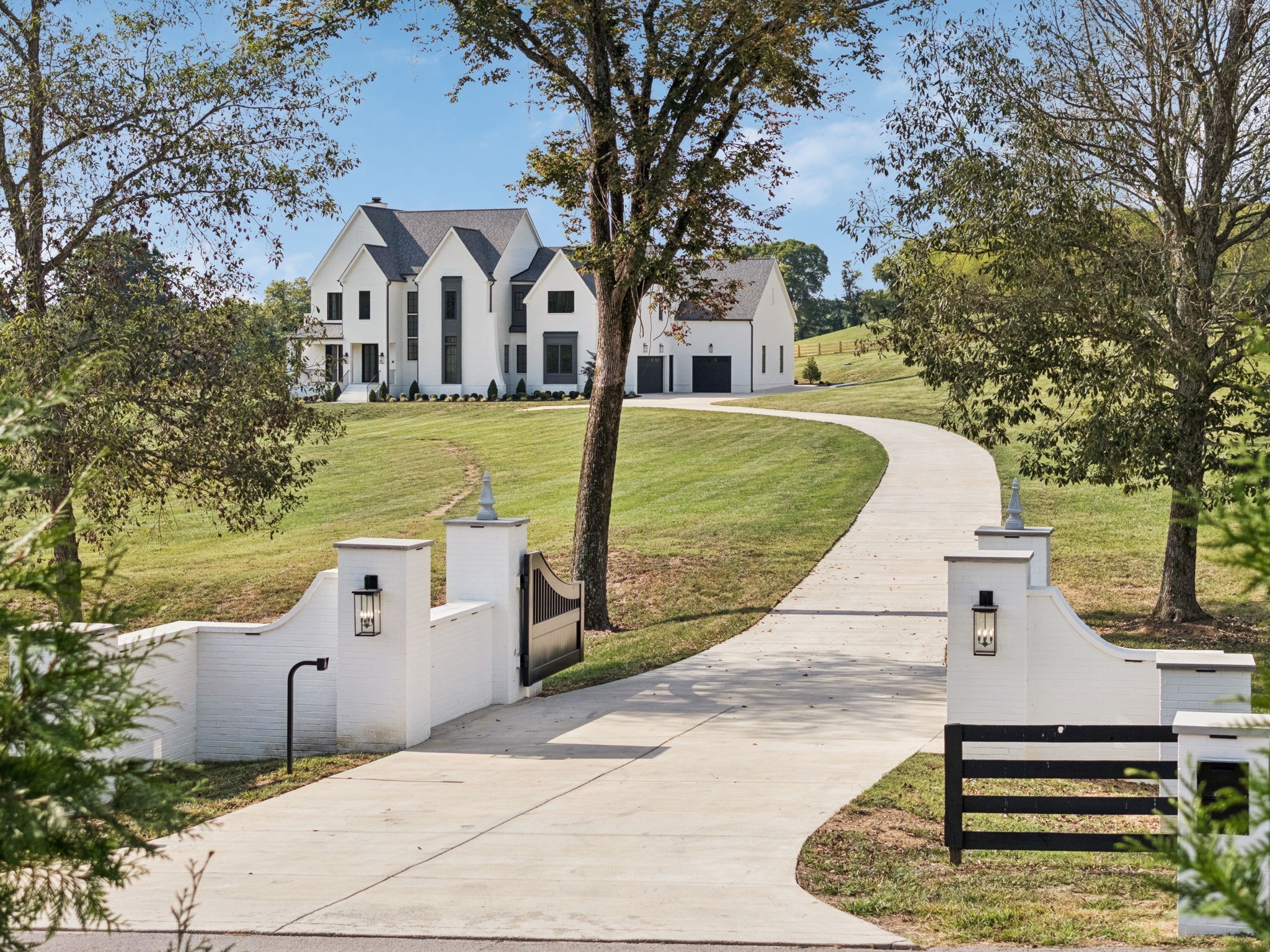 Welcome to this timeless painted brick estate, gracefully nestled on a picturesque 5-acre lot and framed by a classic Kentucky black horse fence. A Ring camera provides added security, while the wide brushed concrete driveway, complete with a dedicated parking pad, offers both functionality and polished curb appeal. The property is accessed through a private gated entrance, flanked by grand painted brick columns and elegant wing walls that make a striking first impression. Under-ledge lighting casts a subtle, upscale glow, and lantern-style fixtures at the gate enhance both visibility and charm—offering a warm welcome, day or night. A grand iron double-door front entry creates a striking focal point, complemented by a smart home security system with integrated cameras for modern peace of mind. Slate tile flooring, a ceiling fan, recessed lighting, and lantern-style fixtures combine to create an elegant yet relaxed outdoor living space.Inside, the home seamlessly blends high-end design with everyday functionality. The kitchen offers professional-grade appliances, quartz counters, a matching quartz backsplash, soft-close cabinetry, a paneled refrigerator, under-cabinet lighting, and glass-front cabinetry for an elevated finish. A separate scullery adds convenience with a built-in microwave and second refrigerator. The home also features a Culligan smart water softener system for enhanced water quality. Designed with entertaining in mind, the property boasts a custom wet bar with quartz counters, a built-in beverage refrigerator, and abundant storage. Step outside to a fully equipped outdoor kitchen featuring a Napoleon grill, Kamado Joe grill and smoker, and an additional built-in beverage refrigerator—perfect for hosting gatherings of any size. Recreational amenities include an in-ground trampoline, while the expansive grounds provide endless possibilities for relaxation and enjoyment. No monthly HOA. A must see.