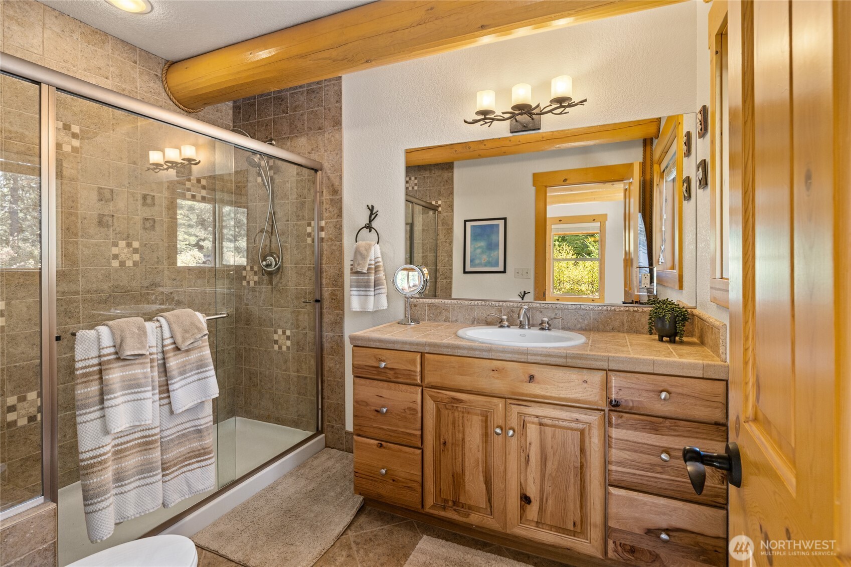 Ensuite primary bath featuring a tiled walk-in shower, generous vanity, and warm natural finishes.