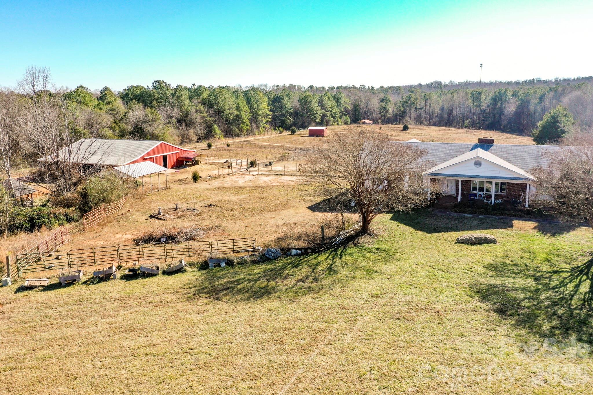 Rare equestrian opportunity on 23.75 acres just 15 minutes from Tryon International Equestrian Center. This versatile property features a spacious home, well-designed barn, fenced pastures, creek frontage, and exceptional potential for future expansion or investment.The 4,000+ sq ft brick ranch offers 4 bedrooms and 3.5 baths with a finished basement. Interior features include a sunroom, home office or craft room, and ample living space ready for customization. Additional improvements include a two-car garage and a detached 24’ x 32’ workshop ideal for equipment, hobbies, or storage.Equestrian facilities include a 44’ x 60’ metal barn with 12-foot shed roofs on both sides and a 16-foot concrete center aisle/parlor. The barn is equipped with eight 12’ x 12’ stalls, tack room, half bath, medications room, and wash area—well suited for private use or boarding operations.The farm is serviced by public water and consists of gently rolling, mostly level pastureland with a small creek. Approximately 850 feet of road frontage provides multiple potential building sites along the road and throughout the acreage, offering flexibility for future homes, expansion, or subdivision potential.While the home and farm will benefit from updates, this property presents an outstanding canvas for renovation and long-term value—ideal for an equestrian estate, family compound, or multi-homesite investment.NEW ROOF JUST INSTALLED - 3/1/2026