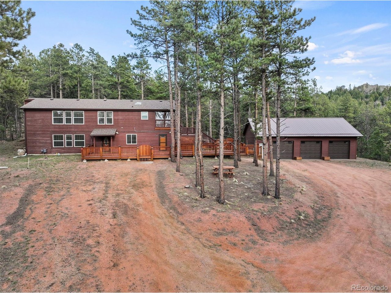 This spacious mountain retreat offers a versatile layout, private setting, and exceptional garage space. This property features an open floor plan, a finished lower level, and a permitted 1-bedroom apartment with private exterior entrance, ideal for income potential, guests, or multigenerational living. The lower level includes a large family room with flexible space for a home office, recreation area, or additional living space, along with a generous laundry room featuring a utility sink, folding area, and extra storage. The bright and open main level showcases a seamless living, dining, and kitchen layout. Two secondary bedrooms share an updated full bath, while the primary suite offers a spacious retreat with a large bathroom, ample closet space, sauna and direct access to a covered deck. The detached 3-car garage is a standout feature, plumbed for in-floor radiant heat, water, & natural gas, as well as having in floor drainage perfect for a workshop, hobby space, or additional storage. The fenced backyard includes a storage shed and room for animals or outdoor use. Surrounded by trees for added privacy, this home combines space, flexibility, and convenience with easy access to paved roads & nearby towns.