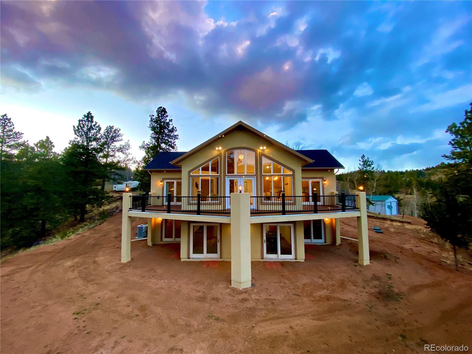 Close in mountain living with breathtaking views! Perfect as a primary home, vacation retreat or investment opportunity - great for an owner occupant or Airbnb. This beautiful custom home on a spacious 3 acre lot backs to open space and features 3 bedrooms (Primary on main, 2 secondary in basement),  2.5 baths, main floor great room, kitchen, finished walk-out basement (family room, 2 bedrooms, full bath) and a detached garage/workshop (2400 fin sq ft home + 720sq ft detached garage). The many windows allow the natural light to cascade in bright & cheerful and showcase the beautiful panoramic mountain views.  The finished basement is perfect for guests or that teen wanting their own space. Beautiful upgrades and finishes including hickory cabinetry, slab granite in the kitchen, porcelain tile in the kitchen, wet bar in the walkout basement and wet rooms (baths & laundry)., vaulted / cathedral ceilings, multiple walk-out access points, custom lighting and more. Equipped with a 50-amp hookup for a hot tub and stubbed for gas on the deck - perfect for outdoor entertaining or just enjoying nature. Surrounded by beautiful foliage including Pine & Aspen Trees.  A woodburning fireplace, 4-ton AC, ceiling fans and r-49 Climate Pro insulation thoughout keeps this home comfortable all year long. Other features include a large garage/workshop with 10' doors and water hydrant, wiring for cable & ethernet; an upgraded 1800-gallon cistern, new septic, a 500-gallon propane tank and 220 service and more. The perfect blend of luxury and comfort makes this home a true oasis. Enjoy all that this stunning home and surrounding area has to offer.  This home is a must see. Amenities abound in this fabulous community including a pool, clubhouse w/fitness center, fenced playground and library. Minutes from the town of Cripple Creek. Don't miss your opportunity.  Welcome Home!