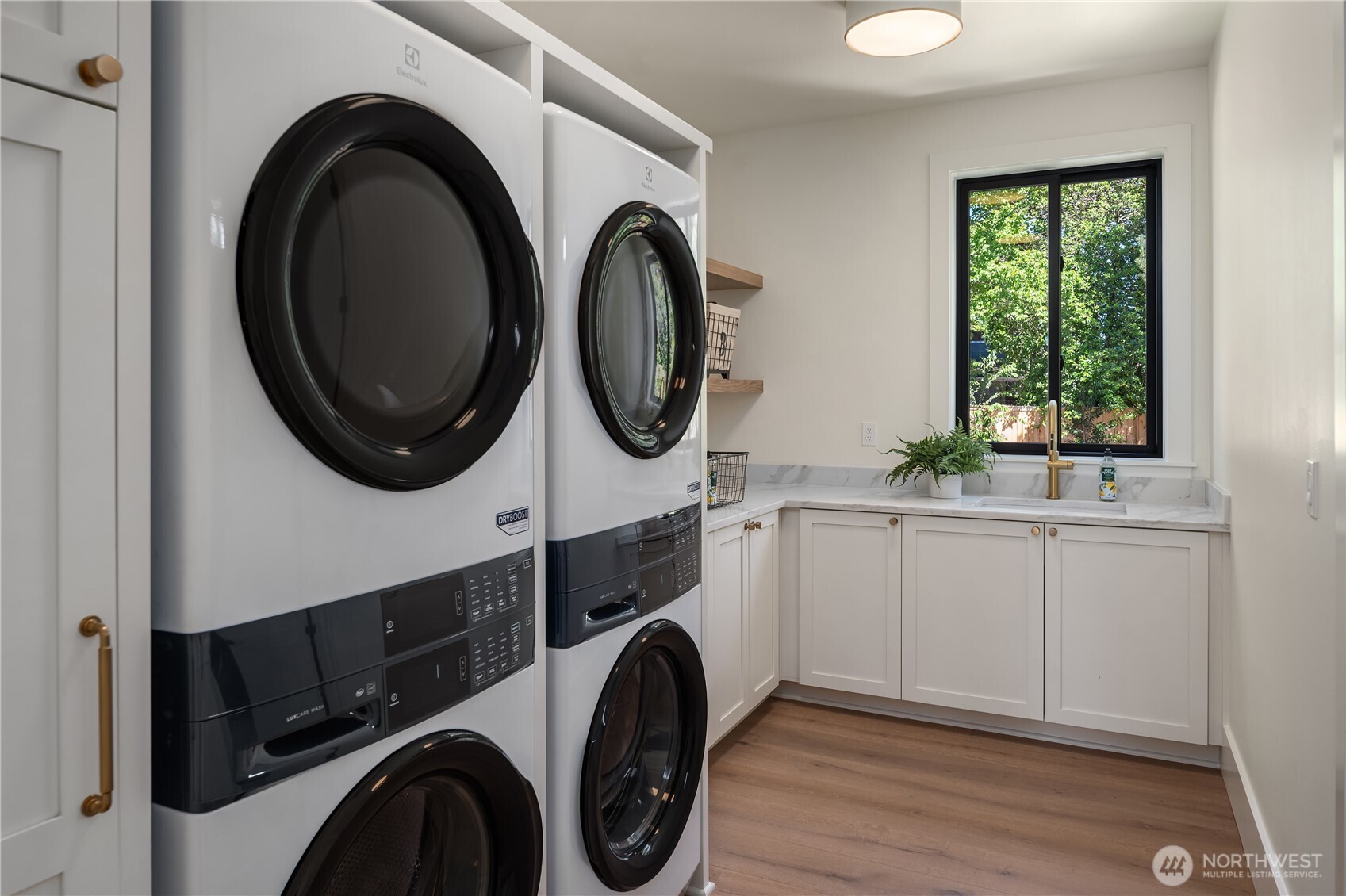 Laundry room pairs sleek stacked appliances with a utility sink