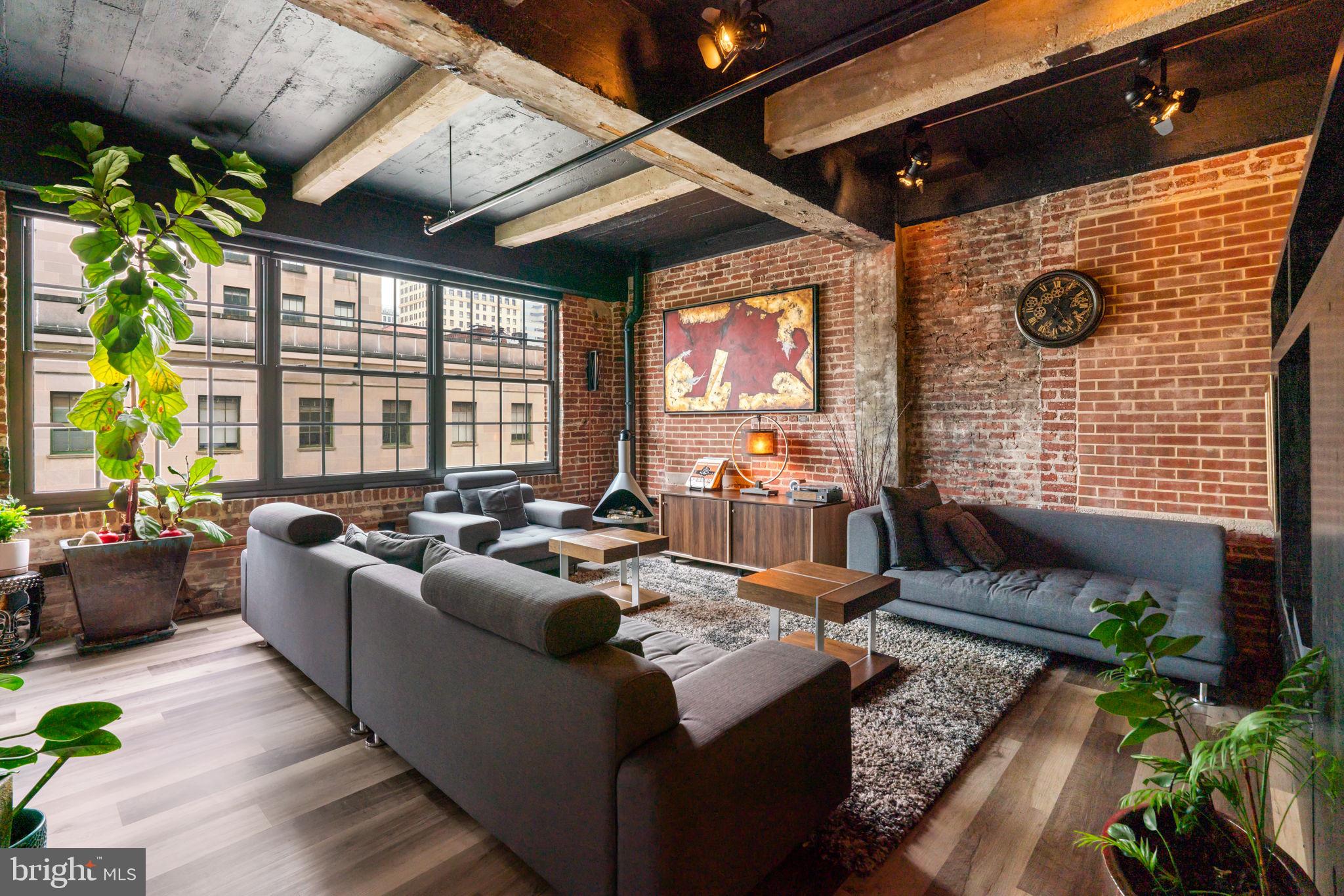 Discover a condo unlike any other in the heart of Downtown Baltimore—a dramatic fusion of design, technology, and luxury living. This 2-bedroom residence with dual primary suites isn’t just smart, it’s brilliantly intuitive. Imagine programming your shower’s temperature and lighting before you even open your front door, or walking into music, climate, and ambiance already set to your preferences. Brilliant Smart Home controls and an integrated Sonos system create a seamless experience throughout, while floor-to-ceiling windows frame breathtaking views of Baltimore City Hall. Every detail has been elevated: custom barn doors, waterproof laminate flooring, a built-in laundry center, and sleek new Samsung appliances. Both ensuite baths are spa-level retreats with smart bidet toilets, heated floor in one bathroom, custom lighting, and a fully reimagined Onsen-inspired wet bath with Moen automated shower and ceiling-fill garden tub. Industrial chic finishes—exposed concrete, refinished pipes, and preserved brick—blend with modern touches like custom closets, smart blinds, a gel fuel fireplace, and upgraded air systems. And for the ultimate convenience, a deeded  garage space big enough for two cars with 2 Level 2 EV charger awaits. This is more than a condo—it’s a lifestyle, engineered for the future.