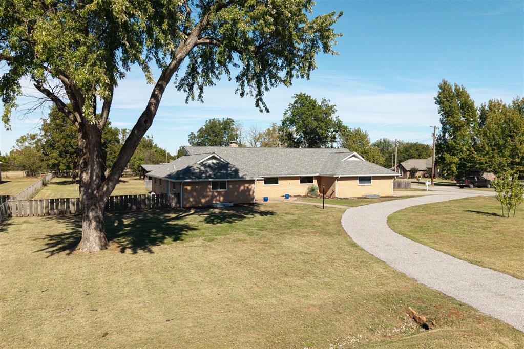 Situated on 1.16 beautiful acres, this thoughtfully updated property blends classic mid-century charm with modern comfort and functionality. Located near quick access to I-35, I-44, and the Kilpatrick Turnpike, this home offers the rare combination of space, style, and convenience. Inside, you’ll find two spacious living areas, two dining spaces, four bedrooms, and three full bathrooms, providing a flexible layout perfect for entertaining or everyday living. The remodeled kitchen is a showpiece—featuring granite countertops, a new sink, induction range with convection oven, stainless dishwasher, and Sub-Zero refrigerator, plus the original wall oven that’s still in excellent condition. Warm mid-century built-ins with pull-out drawers and a convenient pan rack add both charm and function.
The living area has an electric fireplace (convertible back to wood-burning),  brand-new carpet and window coverings (2022). Three bedrooms and both living areas now boast upgraded lighting and ceiling fans thanks to newly dropped electrical (2022). The primary suite includes double closets, while the oversized laundry room provides ample storage and workspace. A concrete safe room offers peace of mind. Outside, enjoy your own private oasis! The re-graveled circle drive (2025) welcomes guests in style, while the expansive backyard features raised garden beds, mature trees, and a 20’x30’ permitted shop equipped with heating, wall AC, and its own separate electric meter. A private well is also accessible (not currently in use). Updates include: roof (2020), HVAC (2013), windows (2014), garage door (2018), blower motor (2021), and two new water heaters. If you’ve been searching for a home that offers acreage, updates, storage, and serenity, this is it. Homes like this are rarely available! Schedule your private showing today & come see why this home is the perfect blend of city convenience and country calm. 30 amp RV plug in back yard, and gas/electric hookups for dryer in laundry.