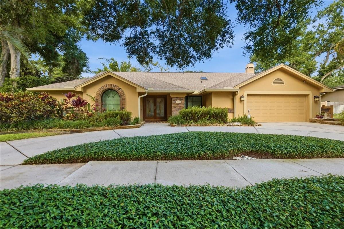 LOCATION, LOCATION. All roads lead to the water from this spacious executive pool home in the desirable Country Woods community. Situated on an oversized 1/3+ acre homesite with majestic trees and lush professional landscaping, this meticulously maintained 5-bedroom, 3.5-bath home offers 3,224 square feet of living space with thoughtful updates throughout.Inside, the home features an expansive open floor plan, Pella hurricane windows and doors, soaring ceilings, multiple skylights, plantation shutters, three remodeled bathrooms, and attractive 20-inch travertine-style porcelain tile flooring throughout. From the circle driveway, enter through stained-glass double doors into a light-filled living room with beautiful pool, backyard, and sunset views.The heart of the home is the spacious kitchen with granite countertops, 42-inch wood cabinetry, stainless steel appliances, an oversized refrigerator/freezer, updated island, breakfast bar, and wine fridge. A nearby eat-in area offers casual dining and pool access. The family room offers custom built-in display shelving, a mantle, and a fully functional wood-burning fireplace. The formal dining area provides ample space for hosting family and friends.The split layout provides function and privacy. One wing includes three generously sized bedrooms, an updated Jack-and-Jill bathroom with tub and shower, and an additional full bathroom with direct access to the lanai and pool. Both bathrooms feature new quartz vanities, sinks, and lighting. On the opposite side, the spacious primary suite offers abundant natural light, evening views, an oversized newly painted walk-in closet, and an elegant en-suite bathroom with a garden tub, separate glass shower, granite vanity, basin sinks, and dark wood cabinetry. The fifth bedroom can also be used as a home office, nursery, exercise room, sitting room, or private flex space. An updated half bath with a pocket door is also attached.The outdoor living area is a true private retreat, featuring a heated saltwater pool and spa with cobalt blue tile and a new salt cell. The pavered lanai, wood deck, and travertine stone walkways wind through tropical landscaping, creating a peaceful setting surrounded by open green space. Five rooms with direct access to the pool, and multiple windows overlook the spa and backyard.MAJOR UPDATES include a roof and skylight installed in 2022, six-foot architectural aluminum backyard fence in 2022, two-unit AC system in 2018, updated blower and ducts with UV protection in 2026, exterior paint in 2017, interior paint in 2018, garage door spring in 2025, pool heater and pump in 2025, refurbished irrigation system in 2021, lanai serving cabinet with quartz counter in 2018 and plumbing for a sink added in 2025, induction stove/range in 2021, Bosch dishwasher in 2021, GE Wi-Fi-connected washer and dryer, whole-house water re-pipe and water heater in 2025, rehabbed garage walls with fresh paint and resurfaced polyurethane flooring, and full-house gutters with leaf guards in the front and pool cage in 2026.The oversized garage includes shelving, a workbench, storage alcove, and an attached concrete shed, providing excellent storage for tools, toys, and equipment. Country Woods offers a convenient location near grocery stores, restaurants, bike rentals, the Pinellas Trail, and the award-winning Gulf beaches of Honeymoon Island and Caladesi Island. View the virtual tour for additional photos of this exceptional home.