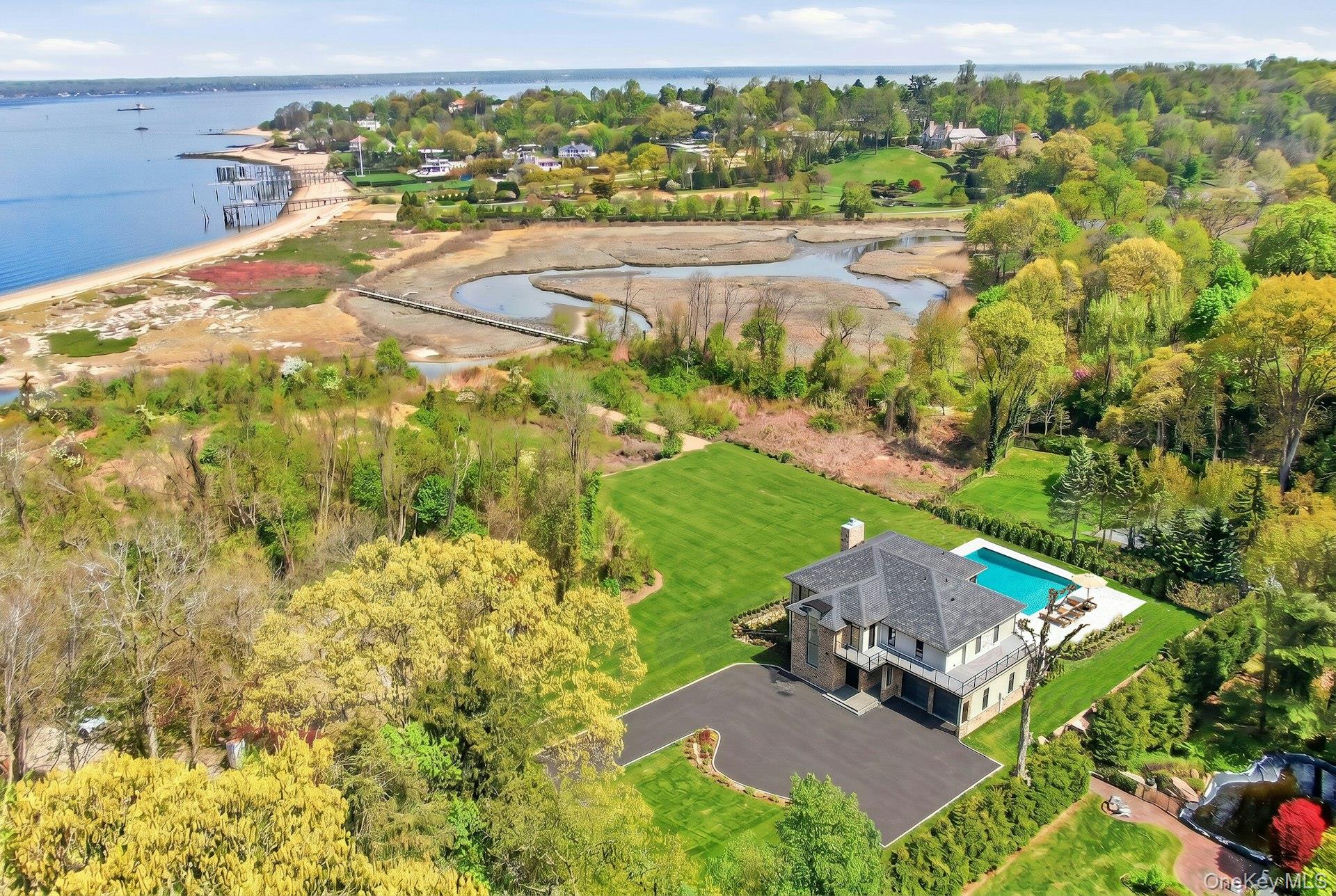 29 Soundview Lane, an exceptional new construction set on a quiet cul-de-sac in the heart of Sands Point, masterfully designed by distinguished architect TJ Costello. Situated on two private acres with sweeping open water views and beach access, this exceptional home blends timeless architectural elegance with modern luxury across every detail.Featuring 6 generously proportioned bedrooms and 6.5 designer bathrooms, the home was thoughtfully curated for both grand-scale entertaining and elevated everyday living. The upper level features a spectacular primary suite with a private balcony overlooking the property and water views. Completing the second floor are three additional ensuite bedrooms, a large recreational space, and a fully equipped laundry room. An additional ensuite bedroom on the main level offers ideal accommodations for guests or multigenerational living, combining comfort and convenience with privacy.Upon entry to this grand home, you are greeted by a dramatic open staircase that serves as a striking architectural centerpiece, while expansive walls of glass frame the surrounding landscape and water views. Seamless indoor-outdoor flow leads to an expansive patio directly off the living room, creating the perfect setting for entertaining and outdoor dining. The chef’s kitchen opens effortlessly into sophisticated living and dining spaces, enhanced by soaring ceilings, abundant natural light, and a seamless open layout designed for modern living.A dramatic walk-out lower level offers an entirely new dimension of entertaining, featuring a fully equipped serving station, custom wine cellar, and extensive recreational and lounge spaces designed for hosting at the highest level, with ample space to accommodate a private gym or wellness retreat. A sixth bedroom and an additional full bath on the lower level provides additional flexibility for extended guests, private staff quarters or an additional home office.The resort-style grounds are highlighted by a large salt water pool with a separate enclosed spa, expansive terraces, and beautifully manicured lawns. A rare offering that combines architectural pedigree, new construction quality, and an unparalleled setting, 29 Soundview Lane delivers modern coastal living at its finest in one of the North Shore’s most coveted enclaves.