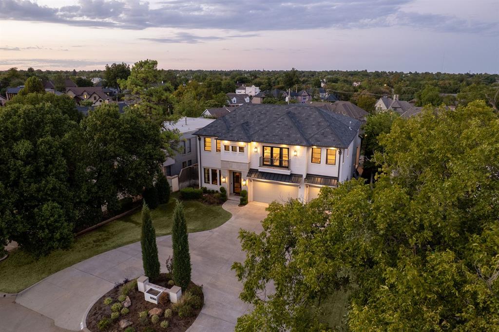 Refined, warm and exceptionally well placed near Nichols Hills Plaza and Kite Park. This home offers Nichols Hills living at its best. Built in 2018, the exterior pairs white brick with masonry accents, black-framed windows and a tailored profile. Updates over the last year have added warmth, texture and architectural detail. Hand-scraped, pecan-toned white oak floors and a sculptural iron stair give the entry a beautiful welcome. The living room is anchored by a Texas Hill Country stone feature wall, cast-stone fireplace and arched cabinetry. It opens to the kitchen, breakfast area and circular bar. The redesigned kitchen features a 48-inch Wolf range, Sub-Zero refrigeration, steam oven, built-in espresso station and island seating. A scullery includes a second dishwasher, sink and prep space, while the built-in breakfast banquette adds another gathering spot. Visual Comfort lighting brings a quiet richness throughout. The first-floor primary suite feels private and serene, with a full stone feature wall, outdoor access and a redesigned California Closets closet. The bath includes a freestanding tub, oversized shower and dual vanities. Also on the main level are a formal dining room, color-drenched study with custom built-ins, powder bath, laundry room and drop zone. Upstairs, three spacious bedrooms each have an ensuite bath. One opens to a Juliet balcony; another has treetop views. A large game room with wet bar and a dedicated theater complete the second-floor entertaining spaces. A finished bonus room is currently used as a gym. The covered outdoor living area includes a fireplace, TV, dining space and upgraded outdoor kitchen. Beyond it, the heated pool and spa are framed by waterfalls, sun shelves and fire features, with space for lounging and entertaining. A circular drive and three-car garage add convenience. A beautifully finished luxury home in Nichols Hills with the spaces you want, a desirable location and very little you’ll need to manage.