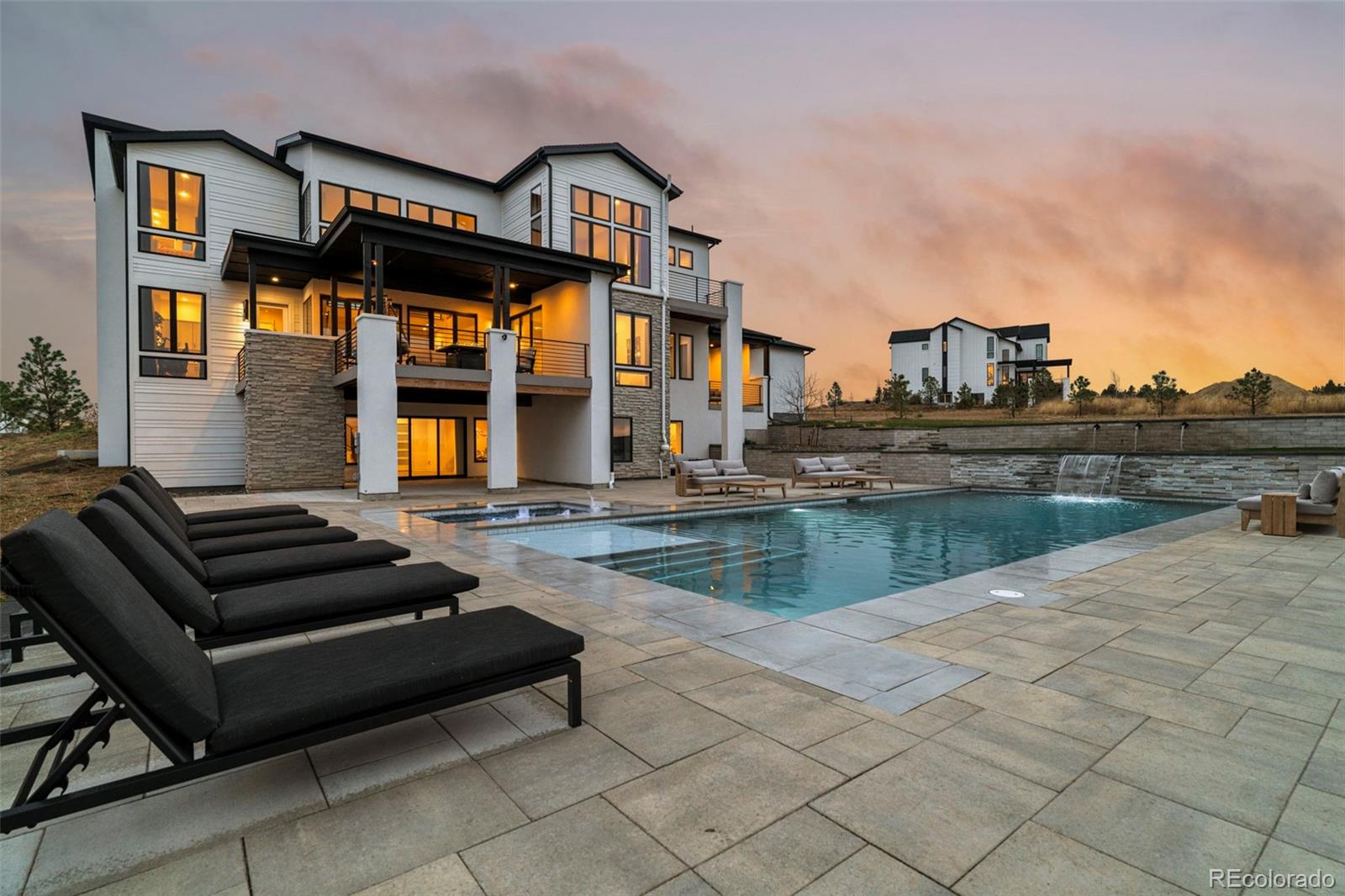 Huge $100,000 Price Improvement! Meticulously maintained two-story modern farmhouse on a quiet cul-de-sac in one of Parker’s most desirable neighborhoods, set on a sprawling 1.5-acre lot backing to open space with beautiful mountain views. Designed by award-winning Joyce Homes, this residence blends modern luxury with sustainable living and features floor-to-ceiling windows, sliding glass panel doors, and seamless indoor/outdoor flow to an expansive covered deck with gorgeous views!. The gourmet kitchen is equipped with stainless steel appliances, quartz countertops, custom cabinetry, and a full scullery kitchen ideal for prep and entertaining. A main-floor guest suite with private bath adjoins a convenient home office, creating a highly functional multigenerational layout. The upper level offers a generous owner’s suite with private balcony, freestanding spa tub, multi-head walk-in shower, and ample closet space. Three oversized secondary bedrooms, a full bath, and an upper-level laundry room complete the second floor. The fully finished walk-out basement provides exceptional natural light and includes a wet bar, 54-bottle glass-front wine room, large great room with modern gas fireplace, fitness room overlooking the pool, and a guest bedroom with adjacent 3/4 bath featuring a steam shower. Outdoor living is unmatched with a heated 20 x 47 salt-water pool, 8 x 10 hot tub, two-tier waterfall feature, and safety covers for year-round peace of mind. An oversized and fully finished 3.5-car garage offers abundant space for vehicles, gear, toys, and hobbies. This extraordinary home combines luxury, livability, privacy, and resort-style amenities in a premier Parker location. Just minutes from the highly rated Legend High School, Colorado Golf Club and The Pinery/Pradera Country Club! Full property tour available at www.9645CanyonWindPlace.com