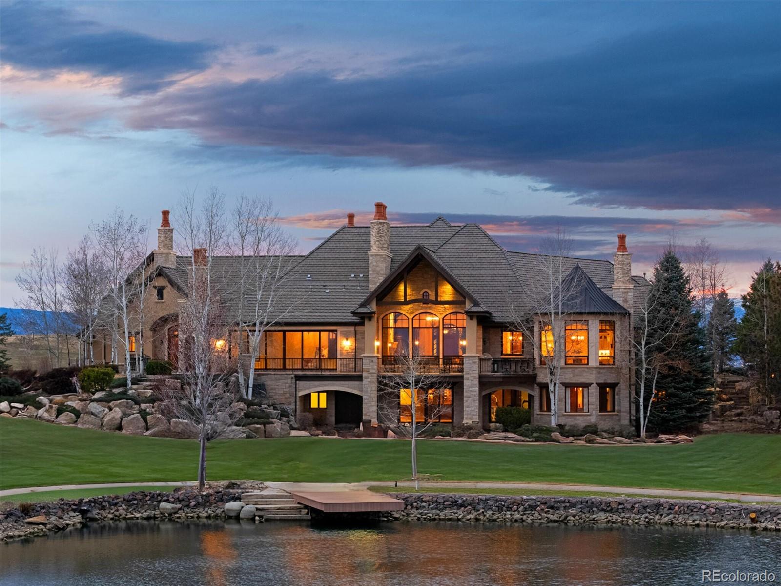 Set on a pristine 1-acre lot at the end of a private cul-de-sac, this estate is a rare sanctuary of luxury and tranquility in one of Broomfield’s most exclusive gated enclaves. From the moment you step inside, soaring ceilings and breathtaking views set the stage for an architectural masterpiece. To the west, the majestic Front Range and Flatirons unfold, while to the east, a private lake framed by towering old-growth trees offers a serene retreat. German-engineered wood windows flood the home with natural light, and radiant floor heating ensures year-round comfort—all seamlessly blending unparalleled craftsmanship with modern sophistication. The gourmet kitchen showcases top-tier appliances—a Wolf gas range, dual Bosch dishwashers, a Sub-Zero refrigerator, dual KitchenAid ovens, and a Miele coffee center—all seamlessly integrated for style and function. The expansive main level boasts three en-suite bedrooms, including a serene primary retreat, while the lower level offers three additional en-suite bedrooms. Entertainment abounds with a state-of-the-art 12-person theater, a climate-controlled wine cellar, and a full bar and game room featuring billiards, shuffleboard, and poker tables. For wellness and relaxation, enjoy the dedicated home gym or retreat to the indoor-outdoor atrium, enclosed by floor-to-ceiling sliding pocket doors. Multiple expansive patios and decks, crafted from Colorado Buff Sandstone, offer breathtaking vantage points to soak in the surrounding beauty. For extended guest stays, a separate lock-off cottage provides complete privacy, featuring two beds, two baths, a kitchen, living room, private laundry, and garage. A hydraulic drive elevator provides effortless access to all levels, while a heated driveway and 4-car garage offer both practicality and prestige. Ideally situated just 30 minutes from Denver, Boulder, and the Denver Tech Center, this exceptional estate offers a rare opportunity to enjoy unmatched luxury, privacy, and convenience.