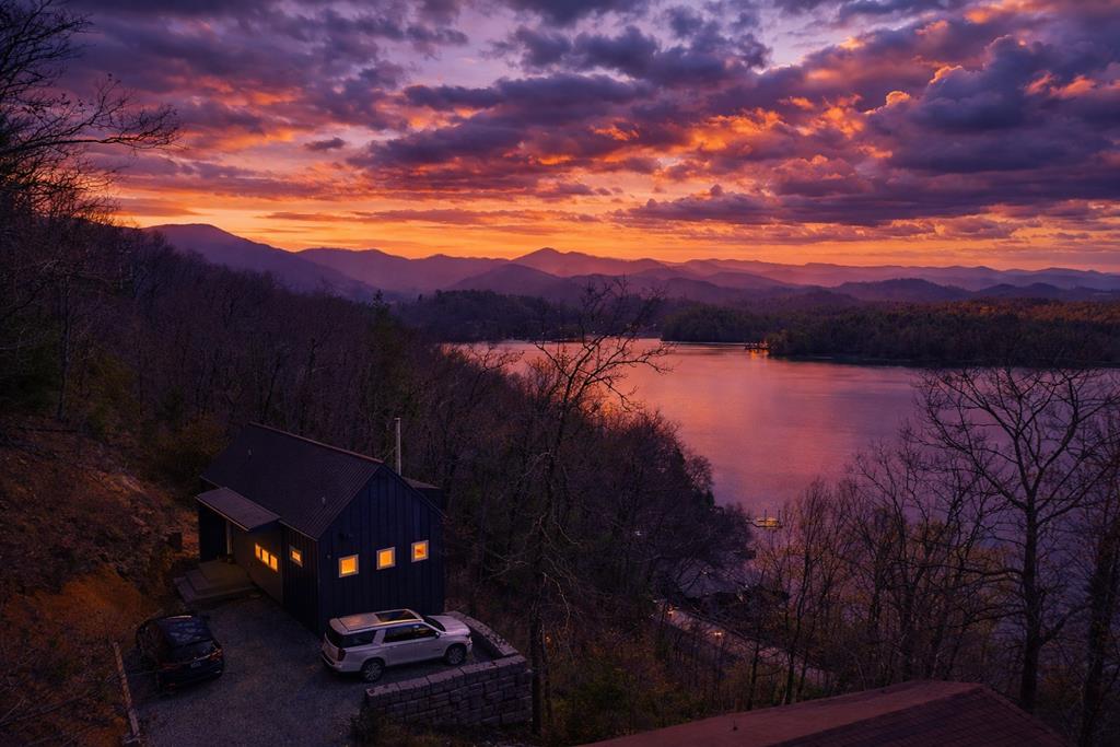 Stunning Lakeview retreat with breathtaking views! Welcome home to this elegant 3-bedroom, 3-bathroom residence nestled in the highly sought-after Thunderbird community on Lake Santeetlah. Built in 2023, this exquisite home offers breathtaking views of Lake Santeetlah and the surrounding mountains from nearly every room, creating a serene backdrop for your everyday living. Main level has an open concept design and features a beautifully designed kitchen, perfect for entertaining, seamlessly flowing into a bright and airy living room that invites relaxation. Enjoy the luxury of a primary suite complete with stunning lake views, offering a peaceful escape at the end of the day. Main level also includes a second bedroom and bathroom, providing ample space for family or guests. The lower level is an entertainment oasis boasting a versatile game area and a cozy second living space, ideal for family gatherings or movie nights. An additional bedroom and dedicated office space make this home functional for both leisure and productivity. Step outside on either deck where you can savor spectacular sunsets over the pristine waters of Lake Santeetlah. Whether you're sipping your morning coffee or hosting evening gatherings, the views from these outdoor spaces are truly unforgettable. With an improved parking area, the home now has enough parking for 3 vehicles. This beautiful property is a rare find. Don't miss your chance to own this slice of paradise! Home would make a great vacation rental or full time residence!