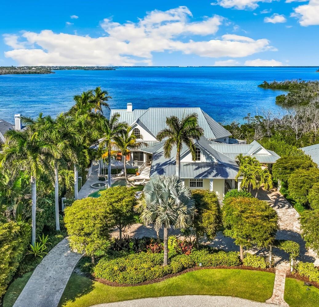 Unparalleled waterfront living awaits at 1689 Jose Gaspar Drive, ideally located on Boca Grande Isles with 122’ of private elevated frontage.  This 4 bedroom, 4.5 baths with 4,500+/- square feet home offers a grande yet effortless indoor-outdoor lifestyle. A sweeping motor court with brick pavers, mature landscaping for privacy, and a double-glass mahogany door entry creates an immediate sense of arrival.   The great room and adjacent dining area, bathed in natural light, is anchored by a coral accented gas fireplace, engineered white oak hardwood flooring, Pecky Cypress beams and a shiplap tray ceiling. The focal point delivers a large wall of retractable sliding glass doors accessing a substantial screened lanai presenting indoor comfort and outdoor splendor with serene views of Sunset Flats and Gasparilla Sound.  The residence features a family room with a wet bar and four ensuite bedrooms meticulously designed with luxurious finishes, plantation shutters, custom millwork, ensuring guests experience unrivaled comfort.  The primary suite is a sanctuary unto itself, complete with a spa-inspired ensuite bath, Jacuzzi tub, oversized shower, and unobstructed northerly water views. The kitchen is a triumph of craftsmanship, featuring honed Mont Blanc quartzite countertops, design lighting, Sub-Zero refrigerator, Thermador double oven, Monogram induction cooktop, U-Line wine refrigerator, a built-in bar with plug-ins and a substantial island anchors the open flow into the living and dining spaces.  While thoughtfully designed, outdoor areas transition effortlessly to a generous custom designed pool/patio, fully equipped outdoor kitchen, ideal for alfresco dining, accessed by multiple doors and walkways. This residence has been thoughtfully curated to deliver effortless luxury, serene seclusion and an unparalleled waterfront living experience. In addition to its commanding bayfront presence, the property includes Hardy siding, standing-seam metal roof, hurricane-impact windows and sliders, controlled One-Touch lighting system, central vacuum system, a whole-home water filtration system, portage, three-car garage, waterfront dock with Ipe decking and shelled walkways surrounded by tropical landscaping.
