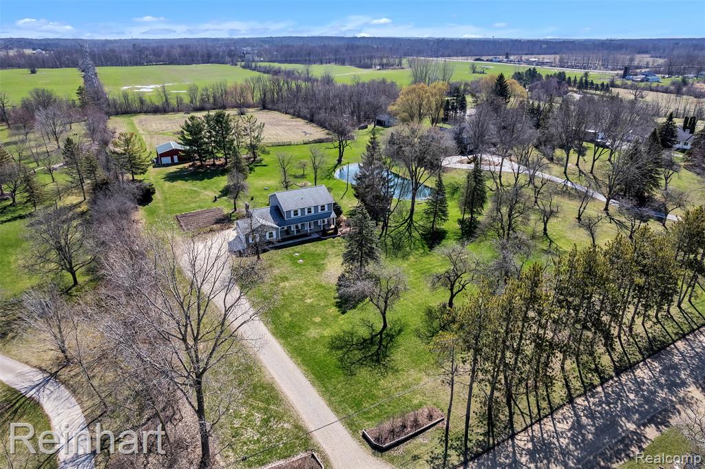 Beautiful colonial set on a rare 5-acre parcel in the highly sought-after Northville School District - an exceptional opportunity to enjoy this much land so close to town! Surrounded by mature trees, open green space, and a picturesque pond, the property offers a peaceful, park-like setting filled with natural beauty, abundant wildlife, and room to roam, garden, or simply unwind by the fire pit under the stars. This 4-bedroom home blends comfort and function, featuring an updated eat-in kitchen that opens to a cozy family room with fireplace and walkout to a private deck overlooking the serene backyard. A first-floor study adds flexibility for work or guests. The spacious primary suite includes an updated bath, while the 4th bedroom is currently used as a large walk-in closet. Additional highlights include a basement w/ workshop & ample storage, plus a barn w/ stalls that is perfect for hobbies, animals, or extra storage. Ideally located near Maybury Park trails for outdoor recreation.