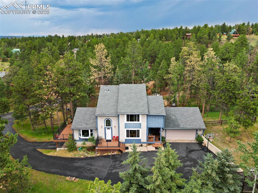 Welcome to your place among the pines! This inviting two-story home is nestled in the sought-after Crestwood Park neighborhood, just a short walk to the community park, playground, and trails—or a quick drive to schools, shops, restaurants, hiking & biking trails, the Woodland Aquatic Center, & Pike National Forest. The home’s exterior features low-maintenance stucco siding with charming blue accents, multiple decks, and a partially fenced 0.38-acre lot—perfect for enjoying Colorado’s natural beauty. Step inside and feel right at home. The bright entryway with soaring ceilings leads you into a sunlit kitchen featuring white cabinetry, solid-surface countertops, a center island for meal prep or gathering, & newer appliances. The eat-in dining nook easily fits a large table for your family and guests. Continue to the spacious living room with a cozy gas fireplace & access to one of four decks for outdoor living and entertaining. A flexible family room offers space for a media area, home office, music room, or reading lounge, & opens to a composite deck with serene views. A powder room & laundry room with access to the oversized two-car attached garage complete the main level. Upstairs you’ll find three bedrooms, including the spacious primary suite with Pikes Peak views, an ensuite bath, and a large walk-in closet. Two additional bedrooms and a full guest bath complete the upper level. The walk-out basement is a true bonus—outfitted as a private apartment with a separate entrance, covered patio, kitchenette (including a full fridge and built-in microwave), full bathroom, and large bedroom. Whether you’re looking to host guests in comfort, accommodate multi-generational living, or generate passive income, this space offers flexibility and value. Live comfortably on the main and upper levels while renting out the lower level for long-term tenants, short-term stays, or seasonal visitors. Don’t miss your chance to call Woodland Park your home, or your home-away-from-home!