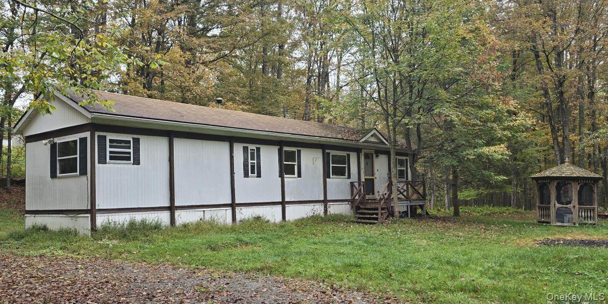 View of home's exterior with a gazebo, roof with shingles, and a yard