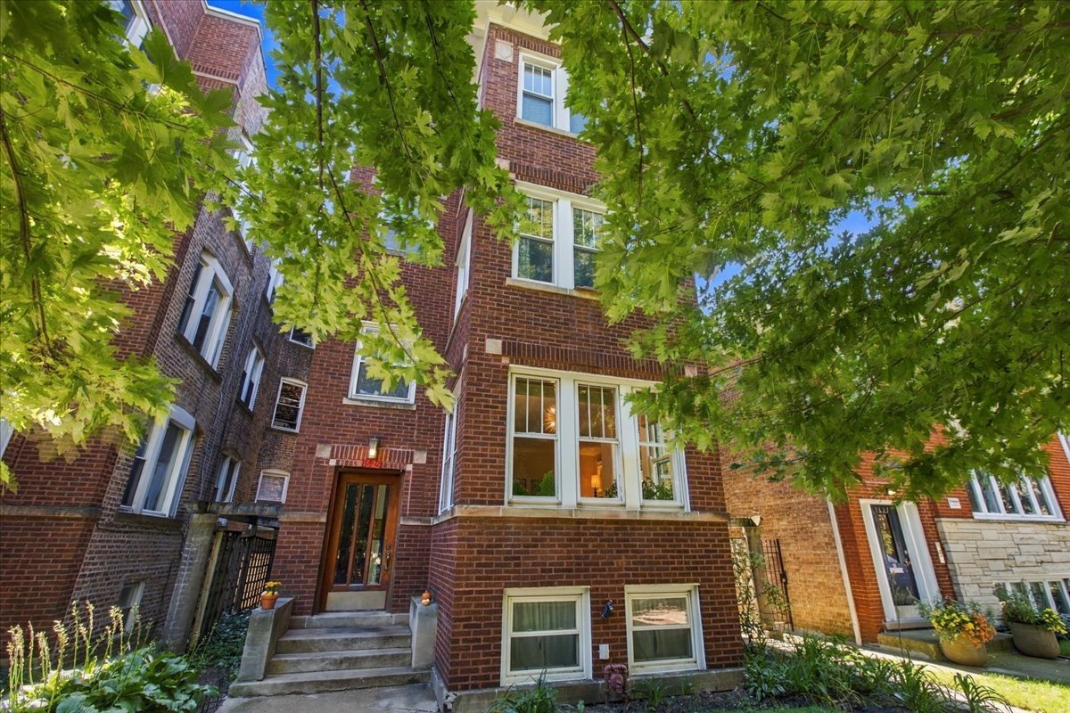 A rare blend of vintage Chicago character and thoughtful modern renovation, this expansive three-bedroom condo occupies a high first-floor in an intimate brick building on a quiet, tree-lined street just steps from the heart of Andersonville. From the moment you enter the generous foyer, the home's exceptional scale, natural light, and attention to detail are immediately apparent. The gracious living room features a wood-burning fireplace framed by beautiful vintage built-ins and opens to a bright sunroom with three exposures -- an ideal spot for morning coffee, a home office, or simply enjoying the changing seasons. The separate dining room comfortably accommodates a large table and flows seamlessly into the oversized eat-in designer kitchen, creating an ideal setting for both everyday living and entertaining. The kitchen features a substantial granite island, stainless steel appliances, abundant cabinetry and storage, and room for a second dining table. All three bedrooms are generously proportioned and offer excellent closet space. The natural-stone spa bathroom features dual vanities and an oversized soaking tub. Throughout the home, original character is complemented by beautiful hardwood floors, custom built-ins, premium new lighting, and sophisticated matte-finish paint. A beautifully landscaped shared backyard provides a peaceful outdoor retreat, while a large private storage room and onsite garage parking are included in the price. Andersonville's restaurants, cafes, boutiques, grocery stores, parks, and public transportation are all just outside your door. Enjoy the character and space of a classic Chicago home with the comfort and style of a thoughtful modern renovation, all in one of the city's most beloved neighborhood settings.