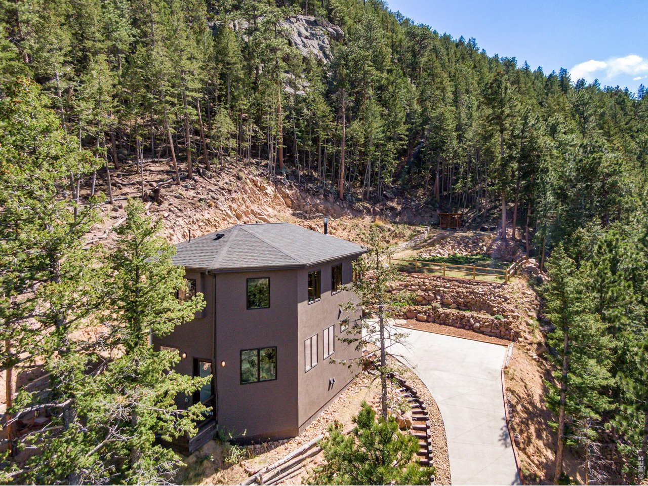 Experience stunning snow-capped mountain and foothill views from this fabulous custom home just minutes from Lyons and Estes Park. Walls of windows frame gorgeous views in every direction, filling the interior with natural light and showcasing the home's crafted character and quality finishes. Set on "Lookout" Drive, the location truly lives up to its name. With privacy, peaceful surroundings, and easy access to nearby recreation, this property would also make an exceptional vacation home or mountain retreat. The home is served by its own reliable well with a 550-gallon extra water storage and is independent from the Pinewood Springs Water District, an important advantage in the area. Inside, the home features inviting living, dining, and kitchen areas; spacious bedrooms with walk-in closets; handcrafted handrails; beetle kill pine ceilings and wood floors; Dolomite counters and tile surrounds; and a functional wood stove with cook oven for warmth and ambiance. The modern kitchen offers stainless steel appliances, a crafted center island with seating, pantry, office space, and access to the large covered porch. Recent updates include a new washer/dryer and refrigerator, newer furnace, and paved, landscaped driveway. Additional features include a whole-house generator, water filtration system, encapsulated storage/crawl space, radon mitigation, central vacuum, high-speed internet, and multiple outdoor play spaces. Estes Park Estates borders Pinewood Springs, with access to local trails and optional PWS Owner's Association membership for reduced propane costs, river park access, and "the Tubs" swimming hole. Enjoy easy access to parks, trails, restaurants, festivals, schools, Rocky Mountain National Park, and surrounding national forest. A must-see mountain property offering natural beauty, peace, privacy, and everyday convenience.