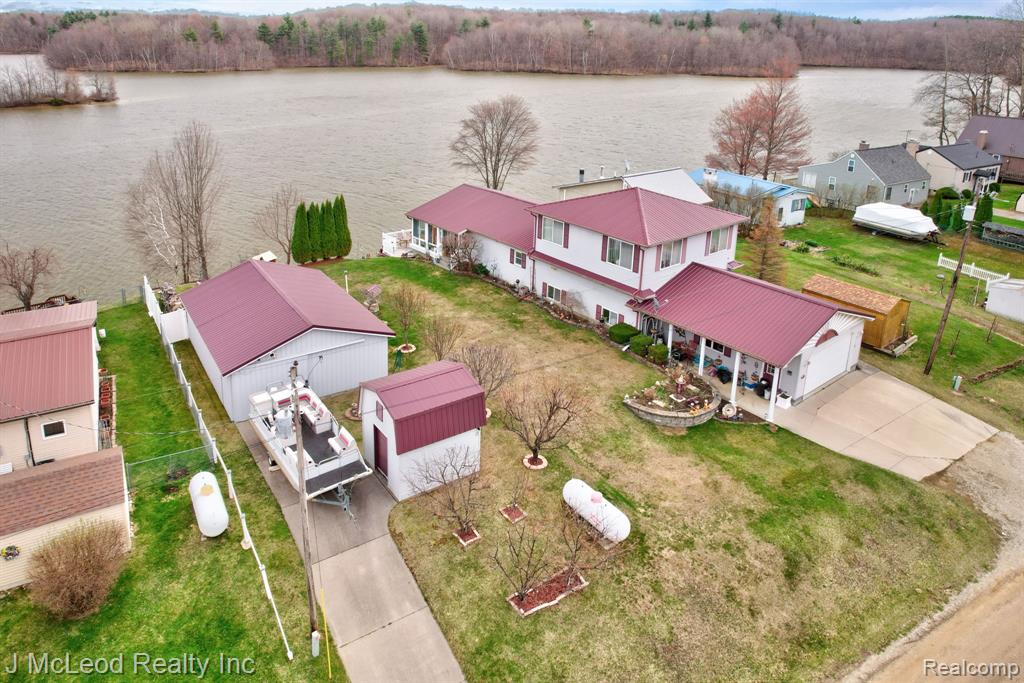 Welcome to lake life at its finest on beautiful Murphy Lake! This spacious waterfront home boasts over 100 feet of frontage on one of the most pristine and sought-after stretches of the lake, offering stunning panoramic views of the widest part of the water. Situated on three lots totaling .33 acres (110x132), this property provides exceptional space and functionality. The exterior is designed for ultimate lakefront enjoyment with a professionally tiered yard, cement paver steps, and an impressive retaining wall leading to Trex decking and steps down to the water. The final tier features paved access to the shoreline, where an aluminum dock is included. Multiple outbuildings offer abundant storage, including a 30x23 pole barn, 2.5 car garage, and three additional sheds—one lakeside shed equipped with electricity and a beverage refrigerator, perfect for entertaining. Inside, you’ll find an open-concept kitchen, dining, and living area ideal for gatherings, along with a main floor bedroom and full bath. A stunning 12x34 three-season room with expansive lake views features a hot tub for year-round relaxation. Upstairs offers a large landing/family room, two additional bedrooms, and a full bath. Adding even more versatility, a portion of the garage has been converted into a private in-law suite complete with a studio-style living space, kitchen, full bath, and laundry—perfect for guests or extended family. Additional highlights include all appliances included, newer windows throughout, and a durable metal roof. Two paved driveways provide convenient access to both the garage and pole barn. Murphy Lake is known for its size, beauty, and recreational opportunities, making it a premier destination for boating, fishing, and relaxing lake days. Located in the charming and quaint town of Millington, you’ll enjoy a peaceful rural setting with small-town charm, while still being just 1–2 hours from Detroit—giving you that sought-after “up north” feel without the long drive.