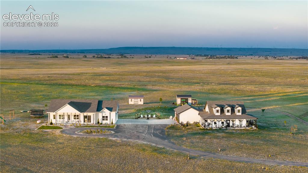Two Homes on 35 Acres — Peyton, CO: Ideal for Multi-Generational or In-Law setup:A rare opportunity: two separate, newer modern-farmhouse homes on one 35-acre parcel — each fully independent with its own utilities and separate meters. An ideal multi-generational or in-law setup: live in one and keep the second as a private in-law residence, guest home, or rental — all under wide-open Colorado sky with Pikes Peak mountain views to the west.Combined Highlights: 7 bedrooms, 4.5 baths, 4,786 finished sq ft total, 6 car garage, shared well & septic, and 35.41 acres zoned A-35 with room for horses, equipment, and RV/toy storage (two outbuildings in place - small barn + storage shed).The main home (8720) — ~2,871 sq ft, 4 bedrooms, 2.5 baths across a bright main level (11–12 ft ceilings, 8 ft doorways), 3 car garage, and a fully finished basement. The vaulted, window-wrapped great room puts the kitchen, dining, and living all in front of the mountains — white cabinetry, quartz island, gas cooktop, double ovens, and two dishwashers — anchored by a fireplace and a striking carved-wood barn door. The main-level primary suite features a freestanding soaking tub, tiled walk-in shower, and walk-in closet, and the main mudroom is fitted with two full-size washers and two full-size dryers. The finished lower level adds three bedrooms, a full bath with double sinks, and a roomy family area. Two covered porches — a hanging swing on each, front and back — complete it.The second home (8735) — a complete residence in its own right: ~1,915 sq ft of easy single-level living with 3 bedrooms, 2 baths, a 3 car garage, an open great room, and a kitchen built to gather around (island seating, butcher-block bar, built-in oven, microwave, gas cooktop, farmhouse sink, custom wood hood). The primary bath offers a jetted tub and a tiled walk-in shower. Its signature is a three-way wraparound covered porch with a tongue-and-groove wood ceiling — a sunset porch you'll love.