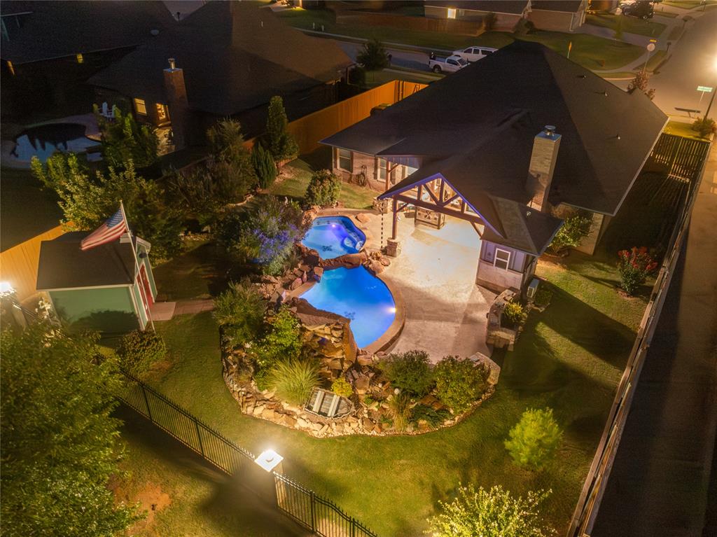 Prepare to be captivated by this one-of-a-kind home in Edmond, featuring a true backyard oasis that defines luxury outdoor living! This stunning 4-bedroom residence, with a flexible 4th bedroom that can serve as a study, showcases a brilliant split floor plan: secondary bedrooms are thoughtfully placed on one side, while the primary suite offers a secluded retreat behind the kitchen. The open-concept living room boasts soaring vaulted ceilings, ample natural light from large windows, and a tiled gas-start fireplace as the central focal point. The gourmet kitchen is a chef's dream with a large center island, granite countertops, built-in appliances, floor-to-ceiling cabinets, and a walk-in pantry. The primary en-suite is equally luxurious, featuring dual vanities, a walk-in shower, and a large soaking tub. Outside, the vaulted-ceiling covered patio with a wood-burning fireplace, a full built-in outdoor kitchen, and an incredible custom pool with rock features creates a private resort. Complete with a 3-car garage, storm shelter, landscape lighting, and a wrought iron fence overlooking a neighborhood greenbelt. Don't miss out schedule your showing today!