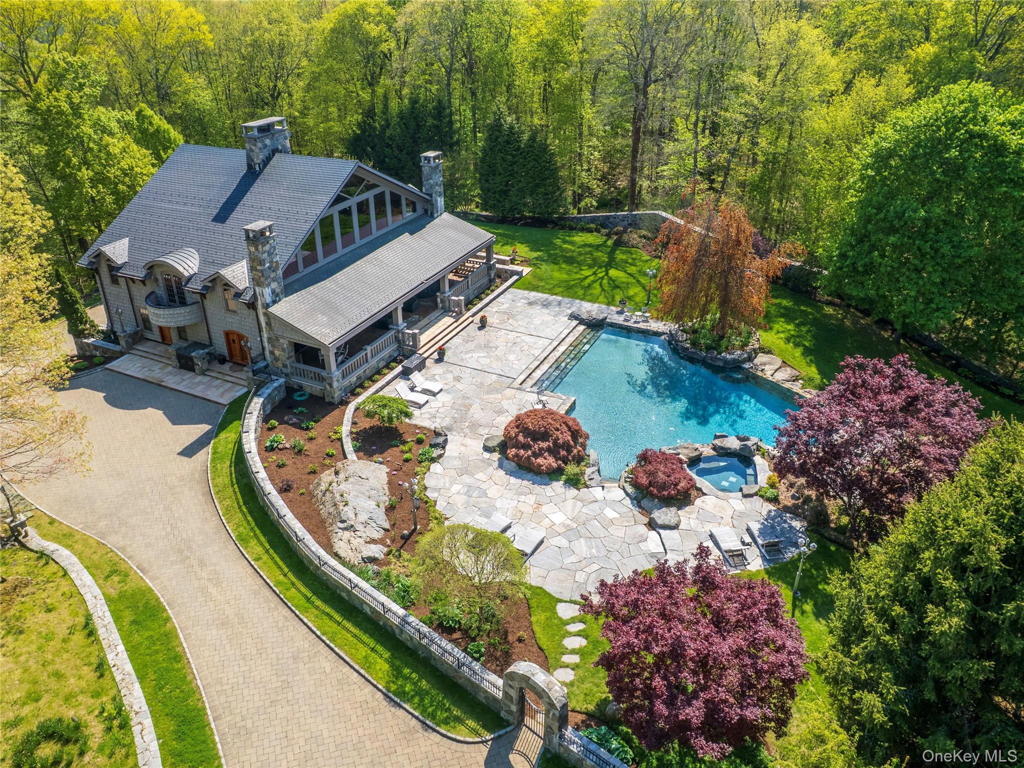 A rare offering where extraordinary craftsmanship, uncompromising luxury, and complete privacy converge to create a residence without equal. Hidden behind a gated entrance and framed by magnificent stone walls in prestigious Bedford, this exceptional estate makes an unforgettable first impression long before you arrive at the front door.  Step inside and discover a world designed to elevate everyday living—where soaring ceilings, dramatic open spaces, and walls of glass create a breathtaking interplay of natural light and architectural beauty. Every inch of this remarkable home has been masterfully crafted with an unwavering commitment to quality, seamlessly blending timeless sophistication with modern comfort.  The main level is designed for both grand-scale entertaining and effortless daily living, featuring expansive gathering spaces, a beautifully renovated chef’s kitchen, and a private guest or in-law suite offering comfort and flexibility for extended stays.  Outside, a resort-caliber setting awaits. A spectacular covered terrace is anchored by a grand outdoor fireplace on one end and a built-in grilling station on the other, with generous spaces in between for elegant entertaining or quiet evenings under the stars. Beyond, an extraordinary custom stone infinity-edge pool, separate stone spa, and sweeping terraces create a private sanctuary that feels more like a five-star resort than a private residence.  Return indoors to enjoy the private steam sauna and Finnish spa on the main level—bringing a true wellness experience into your daily life.  The second floor is dedicated to luxurious private living, highlighted by an exquisite primary suite designed as a personal sanctuary, along with three additional en-suite bedrooms that offer exceptional comfort and privacy for guests.  The lower level redefines home entertainment with an experience rivaling premier private clubs—featuring a custom-designed full bar, a state-of-the-art home theater, fitness studio, and expansive recreation spaces ideal for billiards, celebrations, or unforgettable gatherings.  For the automobile enthusiast, the heated garage comfortably accommodates six vehicles.  Perfectly positioned in Bedford, New York—renowned for its historic charm, estate properties, and timeless appeal—this extraordinary residence offers the ultimate escape from the demands of everyday life while remaining close to exceptional dining, boutique shopping, and equestrian pursuits.  This is more than a home—it is a destination, a retreat, and a once-in-a-lifetime opportunity for buyers seeking nothing less than perfection.
