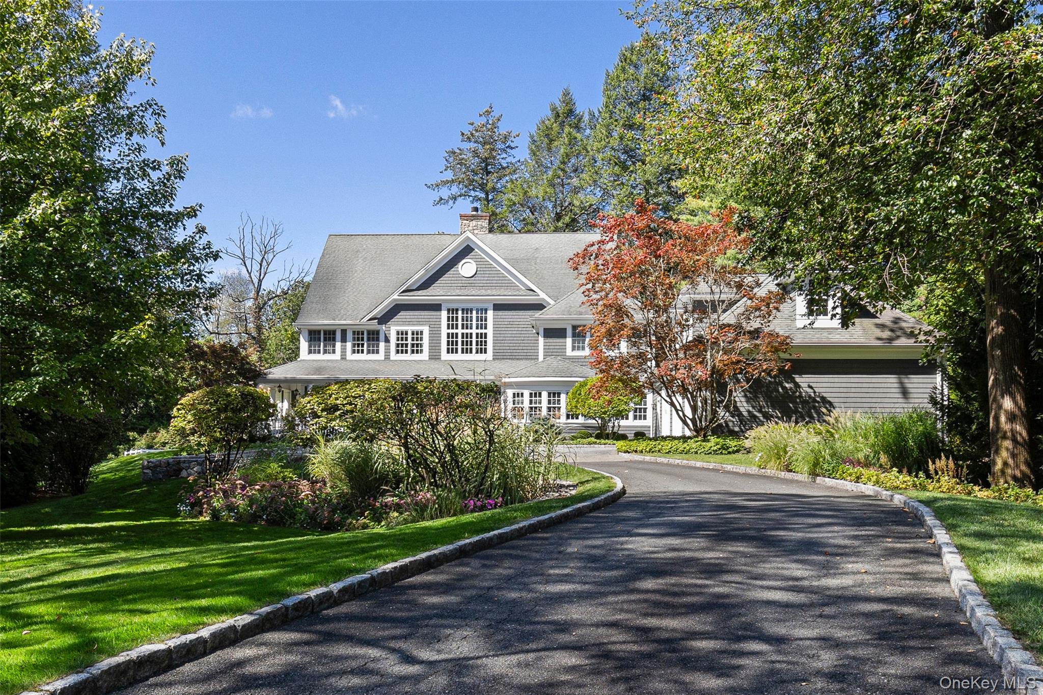 Nestled on 1.5 acres of beautifully landscaped, level grounds in the prestigious Hillandale estate area of Rye Brook, this exceptional newer Colonial exemplifies timeless elegance and modern sophistication. Custom built with the finest craftsmanship, the residence offers 6 bedrooms and 5.1 baths, designed to accommodate today’s lifestyle with effortless grace. A grand and light-filled interior showcases exquisite architectural details, including custom millwork, refined cabinetry, marble and hardwood flooring, and soaring ceilings. At the heart of the home, a Christopher Peacock kitchen with marble counters, an expansive center island, walk-in pantry, and top-of-the-line appliances creates an unparalleled culinary setting. The stunning primary suite serves as a serene private retreat, complemented by generously scaled secondary bedrooms and thoughtfully designed guest quarters. There are many beautifully appointed rooms for entertaining and a home office to complete this exceptional home. Equally impressive, the exterior enhances the sense of arrival and refined living. A long, meandering driveway leads to a heated courtyard and welcoming front porch, while a three-season room and expansive wraparound deck seamlessly connect the home to its scenic surroundings. The property’s setting provides exceptional privacy and tranquility, offering a true retreat from the everyday. Recently and professionally decorated with refined updates, this remarkable home also features ample storage, a three-car attached garage, and a wealth of modern amenities. A rare offering in a coveted estate enclave—this property is truly one of distinction.