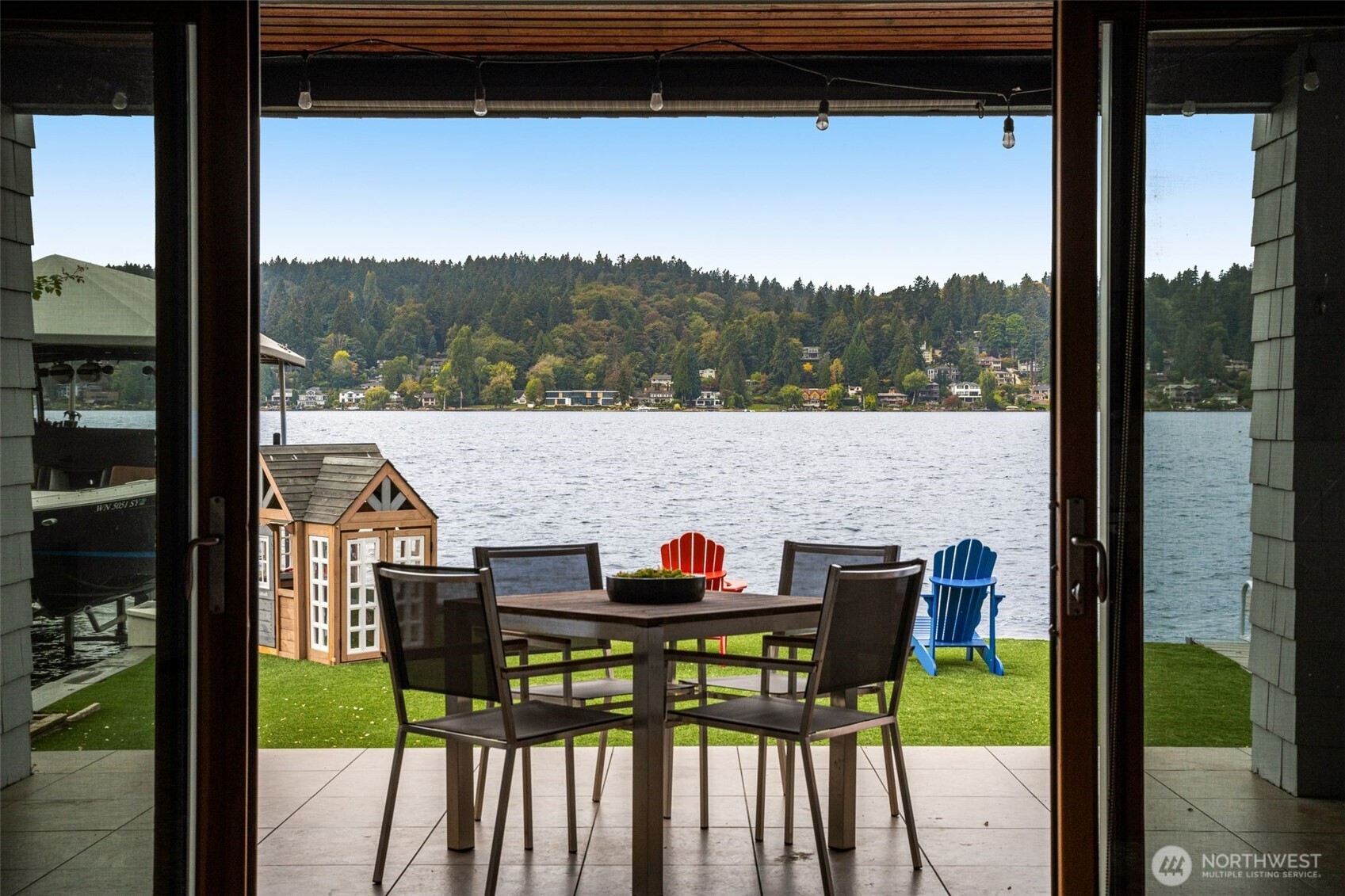 Exceptional Lakefront Living! A rare opportunity to own the only lakefront home in the area with its own private boathouse. Walls of windows and expansive outdoor spaces showcase breathtaking 180-degree water views to the north, west and south, framed by spectacular west-facing sunsets. The open-concept main level flows to a full-length deck, perfect for entertaining and effortless indoor-outdoor living. Chef’s kitchen features DCS, Miele and Thermador appliances, custom cabinetry and Caesarstone surfaces. Upstairs, the luxurious primary suite is joined by two generous bedrooms with a Jack & Jill bath. The upper crow’s nest offers an oversized bedroom, landing and private deck with sweeping lake views. Daylight lower level includes a home gym, fifth bedroom with bath, media/rec room with wet bar, plus washer and dryer. Recent upgrades include new interior and exterior paint, upgraded Lutron lighting, artificial turf and new Trex decking throughout the backyard. At the water’s edge, 40’ of in-house moorage includes a custom boat lift and shore power, plus outdoor moorage and a jet ski lift along 50’ of no-bank waterfront. Existing furnishings are included for a seamless transition to lakefront living. Less than 3 minutes to VMAC—an exceptional location for Seahawks personnel. A distinctive waterfront retreat offering privacy, convenience and a truly exceptional lakefront lifestyle.
