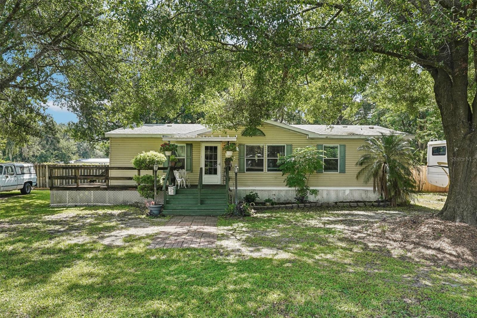 Peaceful Country Living in Plant City – A True Slice of Old Florida Charm!
Welcome to your serene retreat in the heart of Plant City! Tucked away on a beautifully wooded 1.34-acre parcel graced with towering grandfather oaks, this well-maintained 3-bedroom, 2-bath doublewide manufactured home offers the perfect blend of comfort, privacy, and functionality. Whether you're a nature lover, a growing family, or simply seeking a quiet escape from city life, this property checks all the boxes.
With 1,296 square feet of living space, this home boasts a spacious and inviting layout. Inside, you’ll find generously sized bedrooms with oversized closets, two full bathrooms, and an open-concept living and dining area designed for both relaxation and gathering. Natural light pours in, giving the home a warm and welcoming feel throughout. The wraparound wood deck provides the perfect space for morning coffee, evening sunsets, or weekend BBQs with friends and family.

The updated kitchen comes fully equipped with all appliances included, making move-in a breeze. Easy to maintain ceramic tile and hardwood flooring throughout.

Outdoor enthusiasts and DIYers will love the additional features this property has to offer—a charming back porch for relaxing afternoons and a detached workshop/outbuilding that provides ample space for tools, projects, or storage. Whether you're a hobbyist, mechanic, or artisan, you'll appreciate the flexibility and possibilities this space brings.

Located just minutes from downtown Plant City, you'll enjoy easy access to shopping, dining, local festivals, and major roadways while still feeling miles away from the hustle and bustle. It’s rare to find this kind of tranquility, usable land, and functionality—all in one affordable package.

If you're dreaming of peaceful country living with room to grow, play, and create, don't miss your chance to make this one-of-a-kind property your own. Schedule your private showing today!