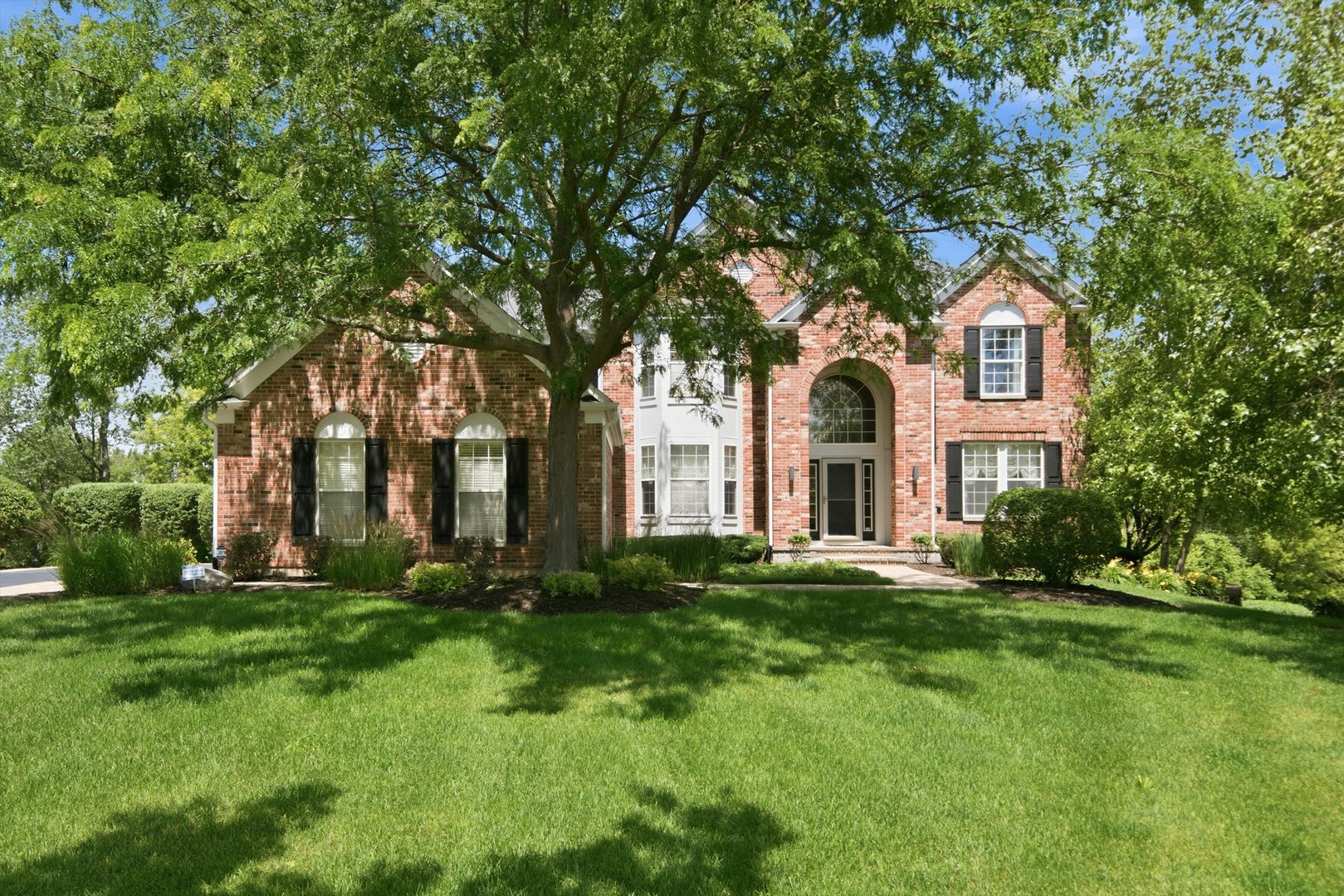 Welcome to this exceptional brick estate, beautifully situated on a quiet cul-de-sac and offering nearly 5,000 square feet of thoughtfully designed living space across three finished levels. Combining timeless elegance with modern functionality, this meticulously maintained home is filled with impressive architectural details, generous living areas, and countless opportunities for entertaining. A grand two-story foyer welcomes you inside, where soaring ceilings and abundant natural light create an unforgettable first impression. The dramatic living room showcases a stunning floor-to-ceiling fireplace and is overlooked by an elegant catwalk that connects the upper-level bedrooms. A sophisticated sitting room and formal dining area provide ideal spaces for hosting holidays and special occasions.   The spacious kitchen is designed to impress with a large breakfast bar island, built-in desk, double ovens, stainless steel appliances, ample cabinetry, and dedicated pantry space. The adjoining breakfast area opens to an expansive deck, creating seamless indoor-outdoor living. A welcoming family room featuring a built-in bar offers the perfect setting for casual gatherings and entertaining guests. The luxurious primary suite serves as a private retreat, complete with an expansive spa-like bathroom featuring a whirlpool tub, separate shower, dual vanities. Additional bedrooms are generously sized, including a private guest suite with its own full bath and beautifully tiled walk-in shower. A dedicated home office showcases rich wood built-ins and custom desk space, ideal for remote work or study. The finished lower level expands the home's versatility with a spacious game room, recreation area, additional full bath, abundant storage space, and endless possibilities for entertaining or relaxation. Outdoor living is equally impressive, with a screened porch that opens to a beautifully designed patio, offering the perfect backdrop for morning coffee, evening gatherings, or enjoying the professionally landscaped grounds. Additional highlights include a large laundry room, extensive storage throughout, a side-load three-car garage, and numerous updates that enhance both comfort and efficiency. This remarkable residence offers the perfect blend of luxury, space, and everyday practicality in a highly desirable location close to parks, schools, shopping, dining, and commuter routes. A rare opportunity to own a truly distinguished home designed for comfortable living and memorable entertaining.