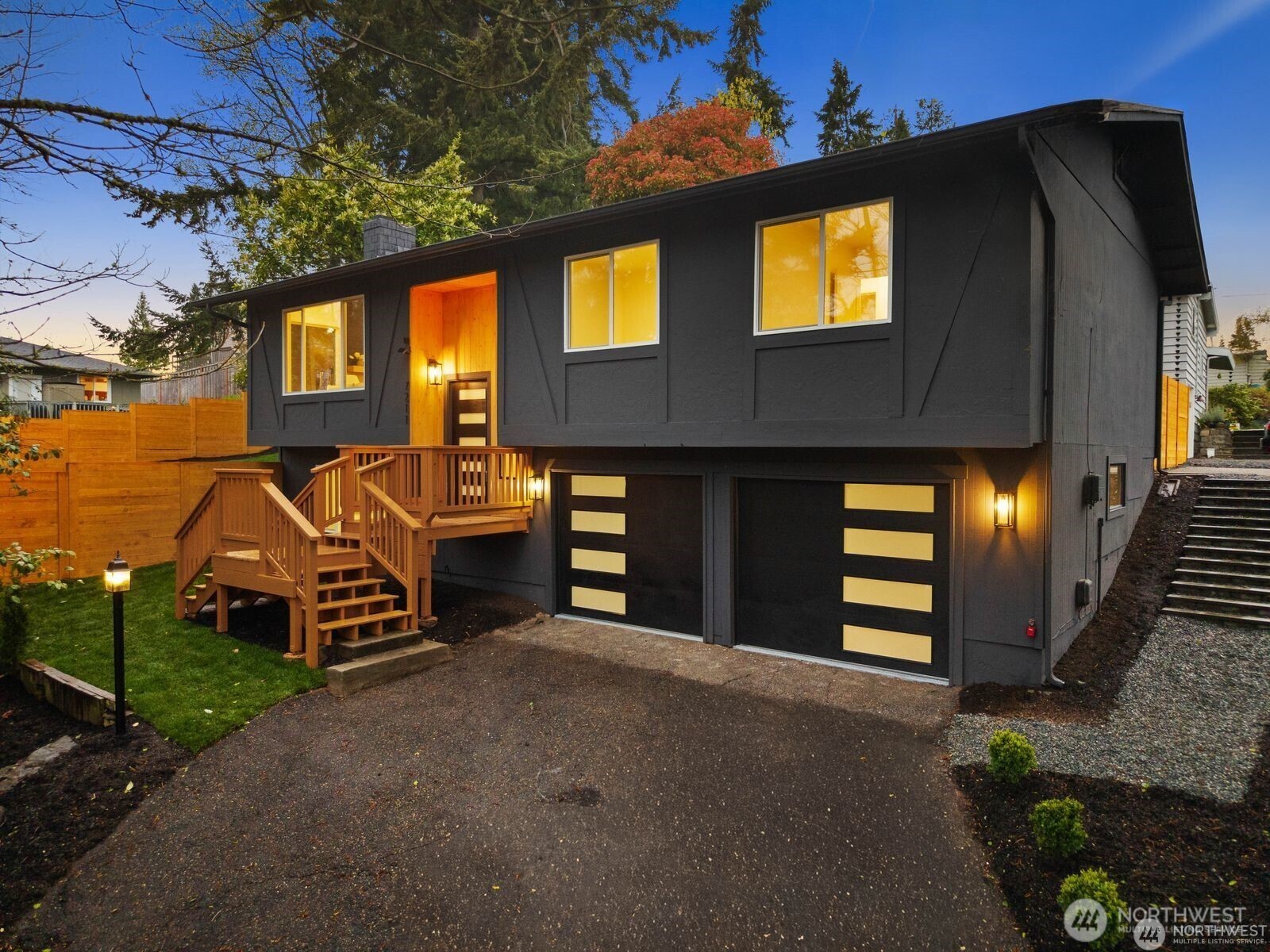 Fully reimagined from top to bottom, this Edmonds home is a study in modern design and quality craftsmanship. A striking charcoal exterior with warm wood accents and fresh landscaping sets the tone from the moment you arrive, situated on a quiet street with mature tree coverage. Inside, the main living level unfolds with intention. Vaulted ceilings and new windows frame a dramatic fireplace with a black brick surround and warm wood accent detail, while the open kitchen delivers marble backsplash, gold pendant lighting, stainless appliances, and a statement island built for gathering. The dining area flows naturally from the kitchen, completing a main floor designed for both everyday living and entertaining. The lower level adds a second living space anchored by its own fireplace and a slatted wood accent wall, offering flexibility for a media room, guest suite, or lounge. The primary suite is a true standout, and every bathroom throughout reflects a designer touch, from geometric wallpaper and brass fixtures to floating vanities and glass-enclosed showers. Major systems have all been replaced including the roof, windows, water heater, and furnace, making this a genuinely move-in ready offering. An epoxy-coated two-car garage, entertainer’s deck, and fully fenced yard complete the package. A rare full renovation in Edmonds.